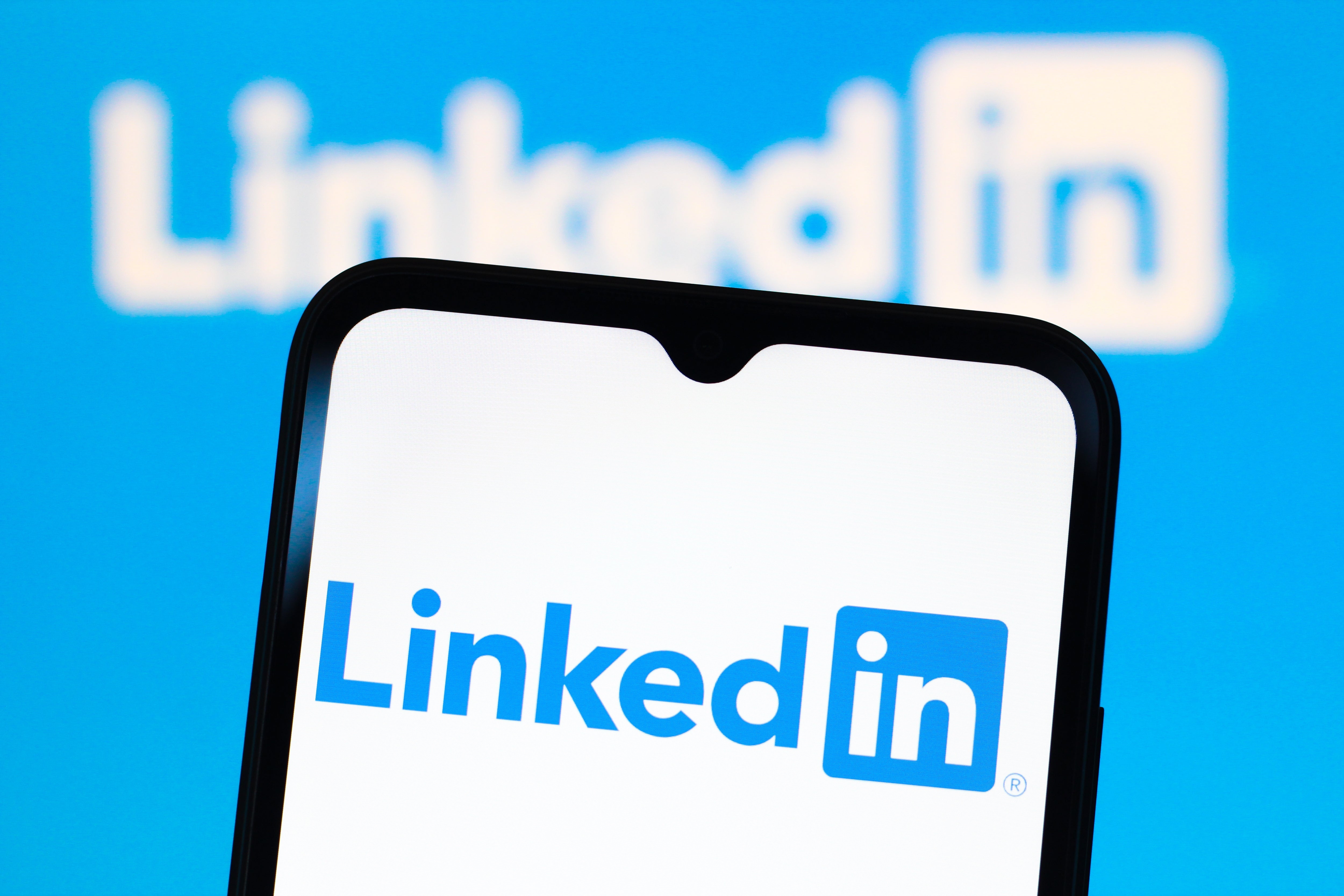 Smartphone displaying LinkedIn logo with blurred LinkedIn background, highlighting the platform's branding