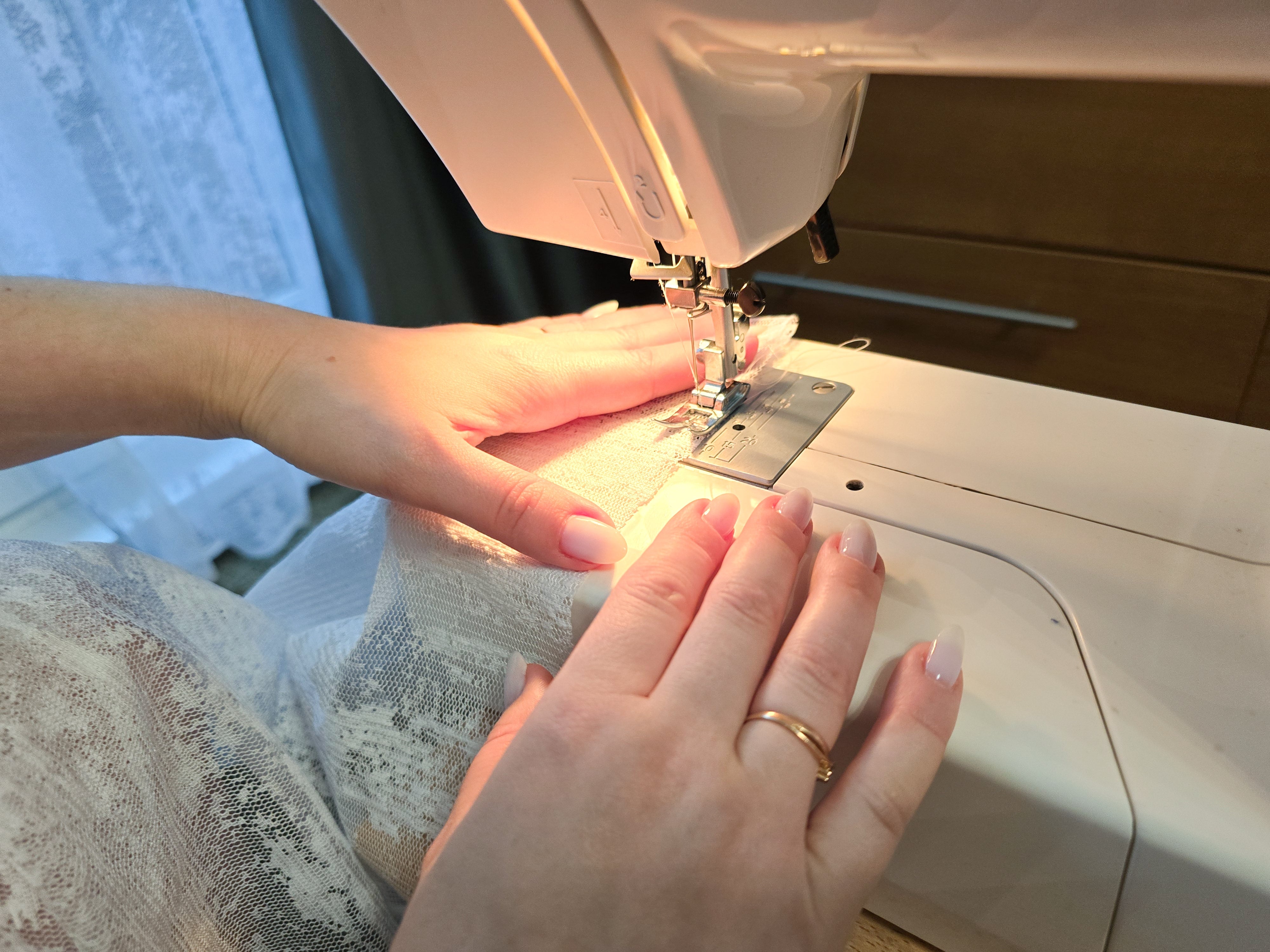 Hands guiding lace cloth  done  a sewing machine