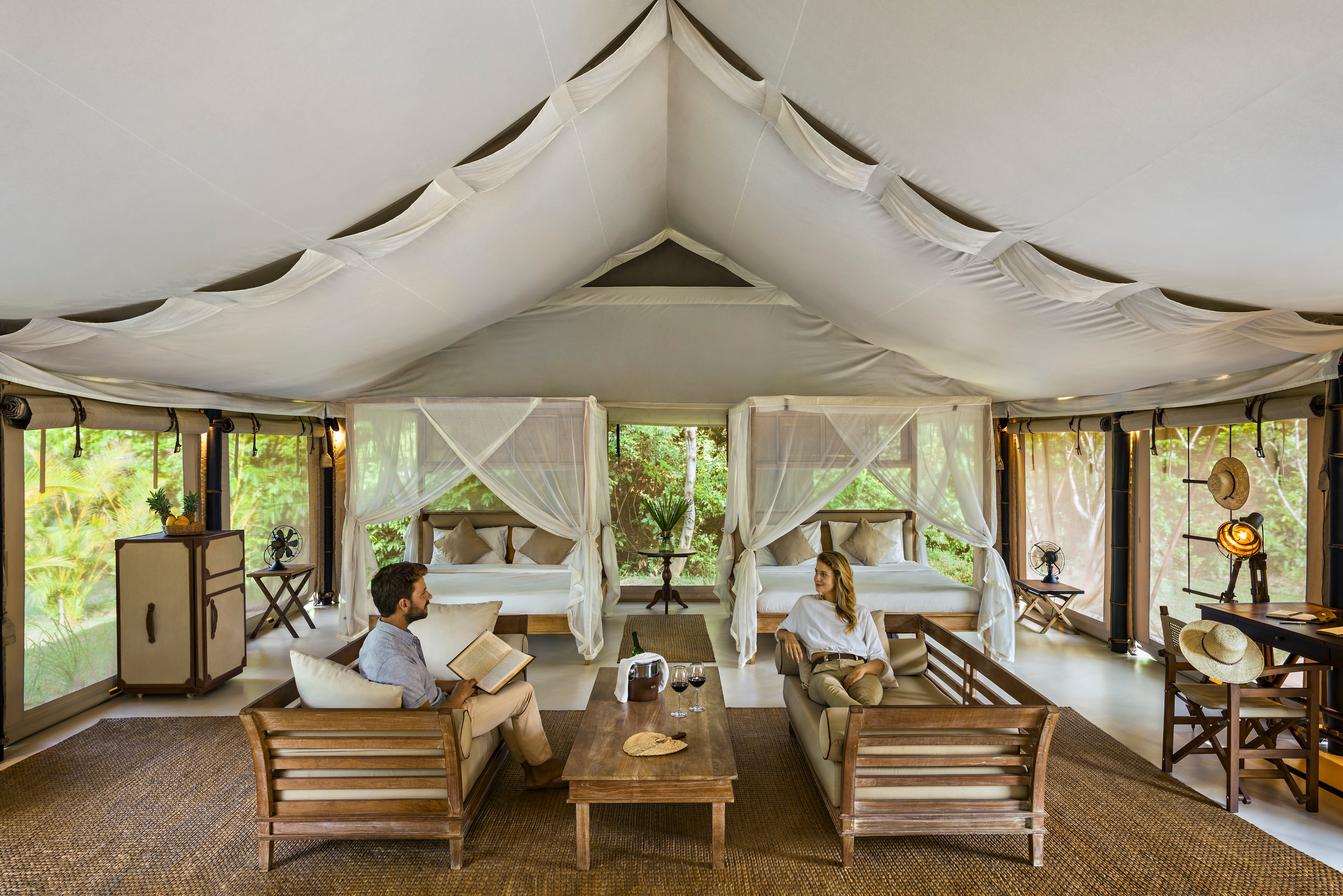 Luxurious safari structure   interior with 2  beds, seating area, and 2  radical   relaxing and reading. Natural airy  and greenery are disposable   outside