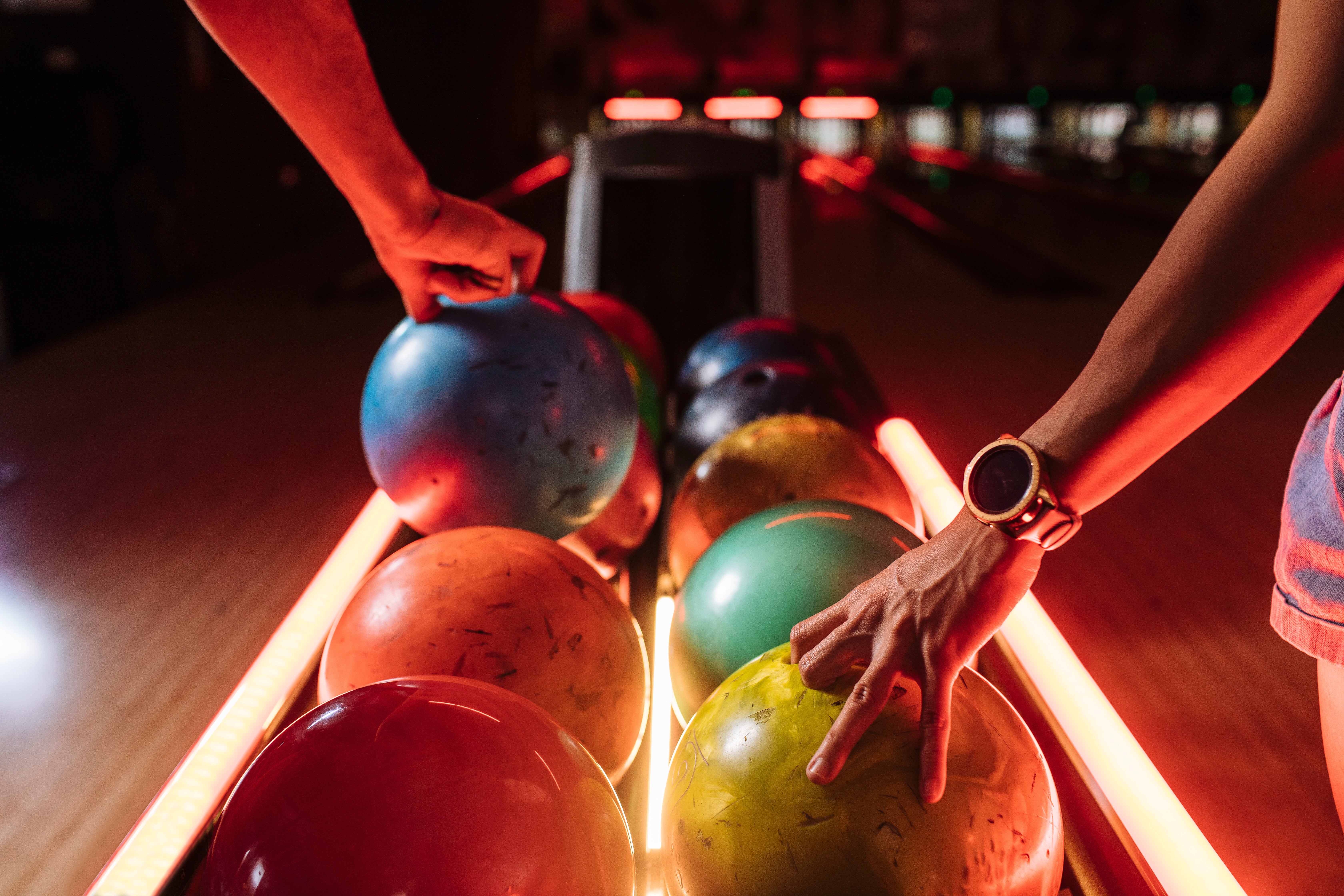 People selecting bowling balls from a rack successful  a bowling alley