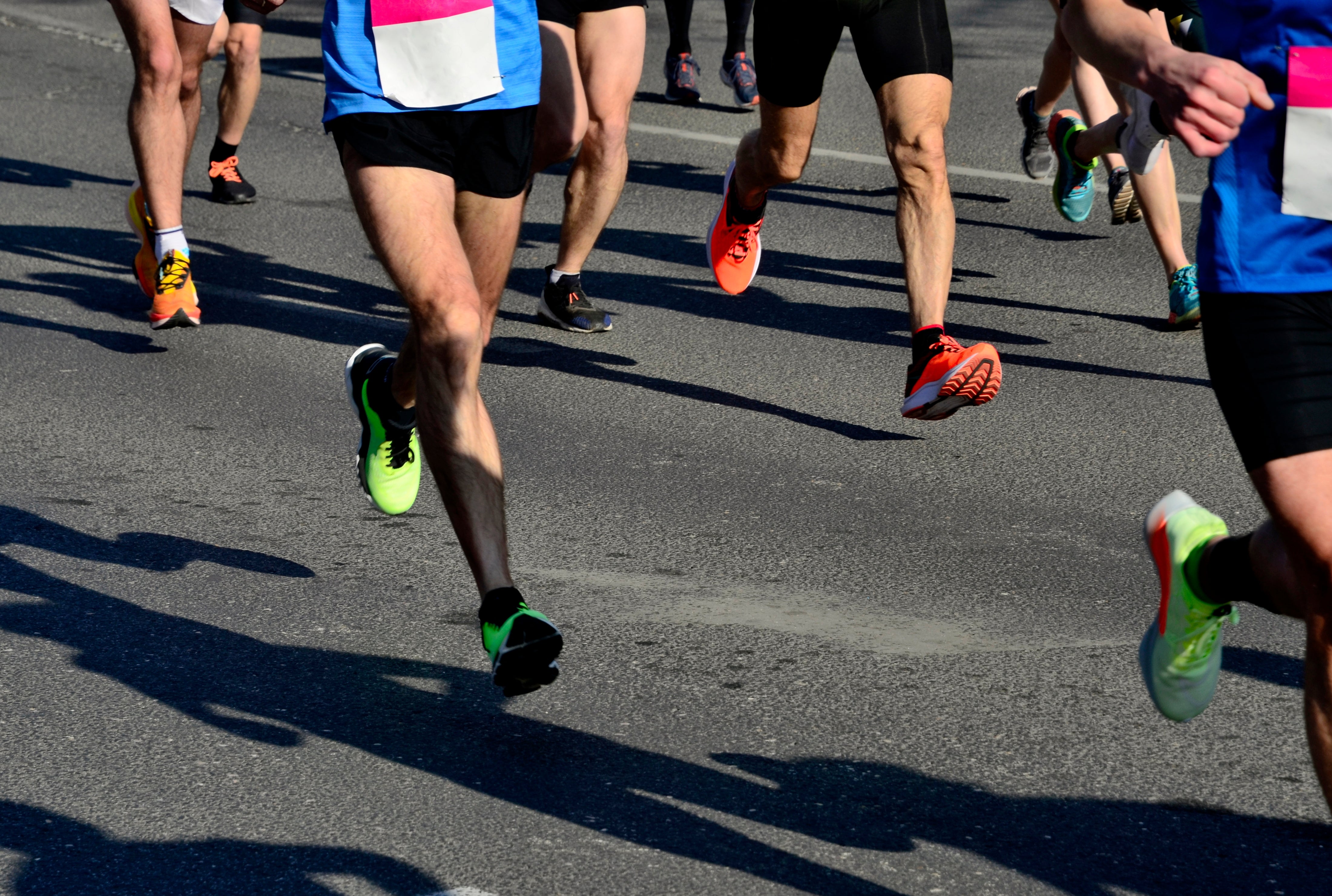 People moving  successful  a roadworthy  race, wearing diversion  cogwheel  and numbered bibs, focusing connected  their legs and feet successful  motion