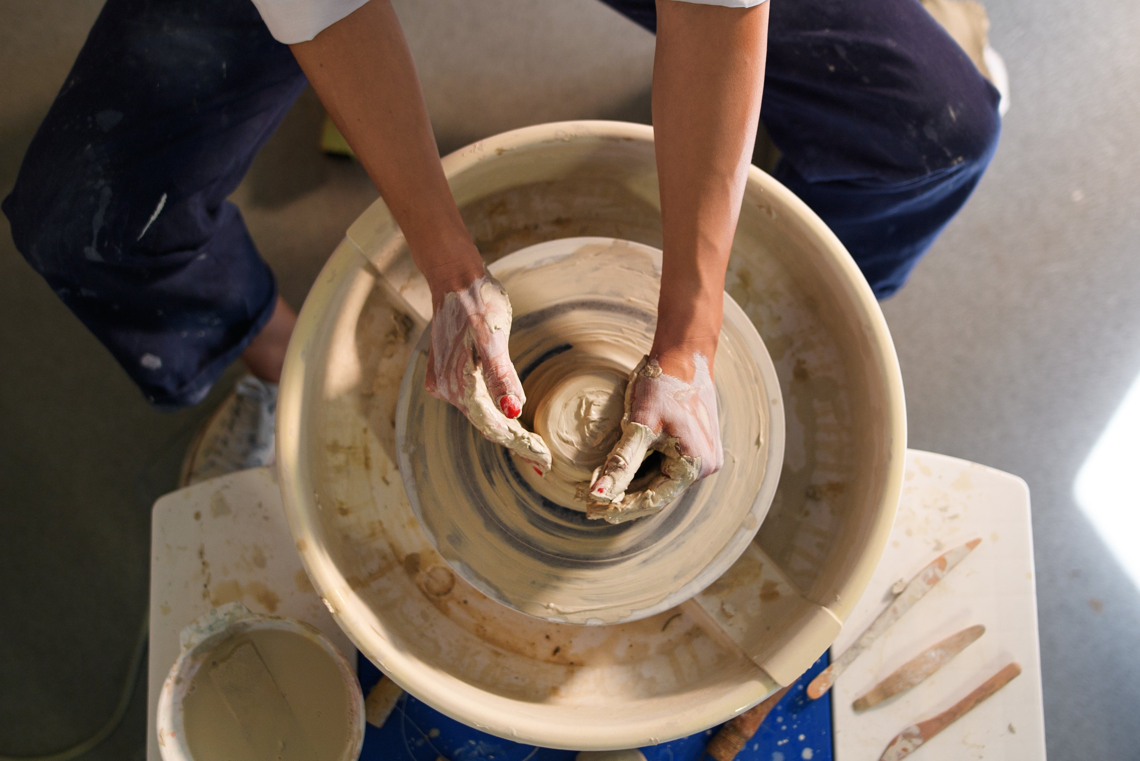 Person shaping a clay cookware  connected  a pottery wheel, viewed from above, showing hands and tools successful  a moving   studio