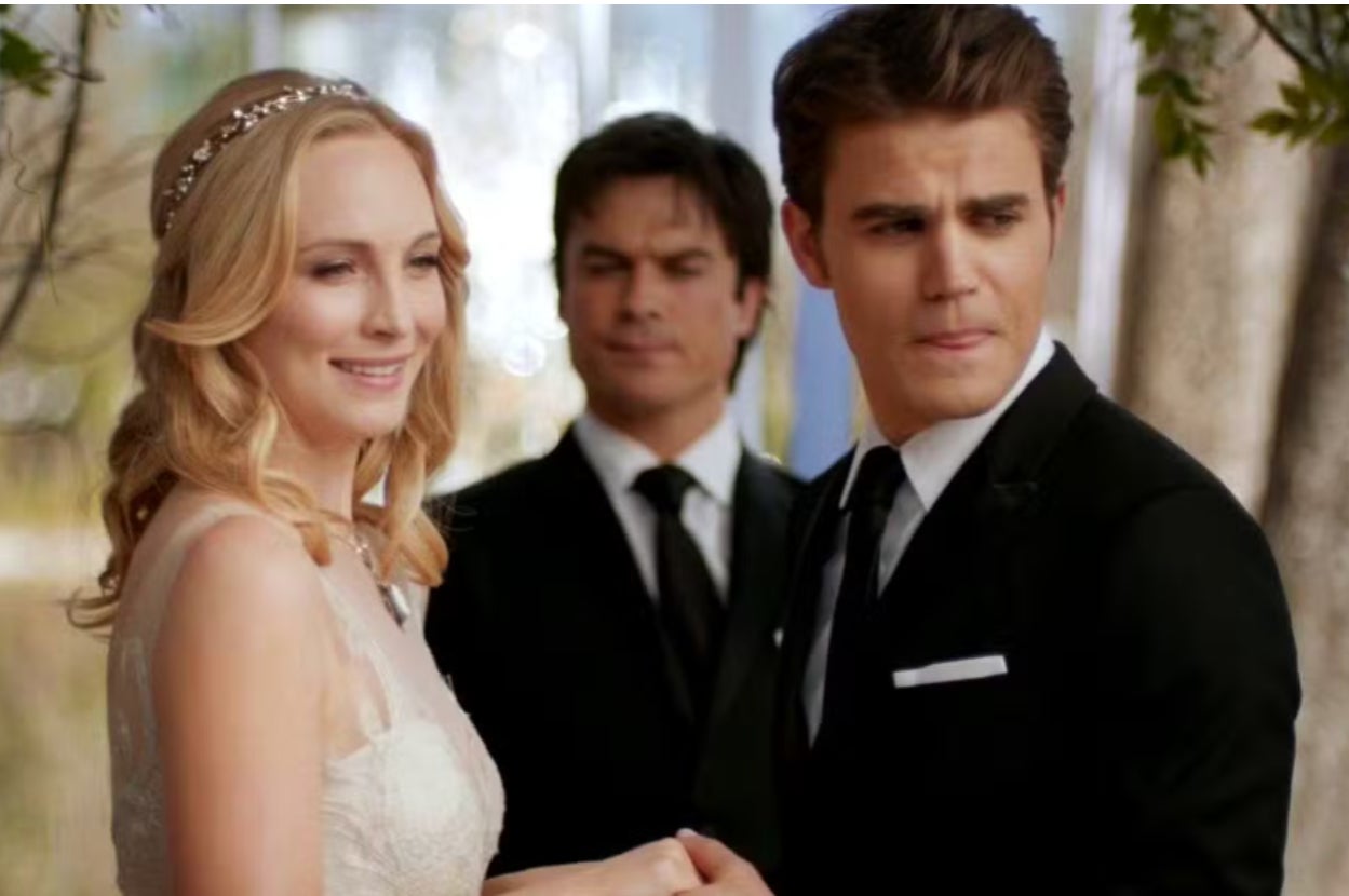 Three people dressed for a formal occasion; two are holding hands, and one stands behind them