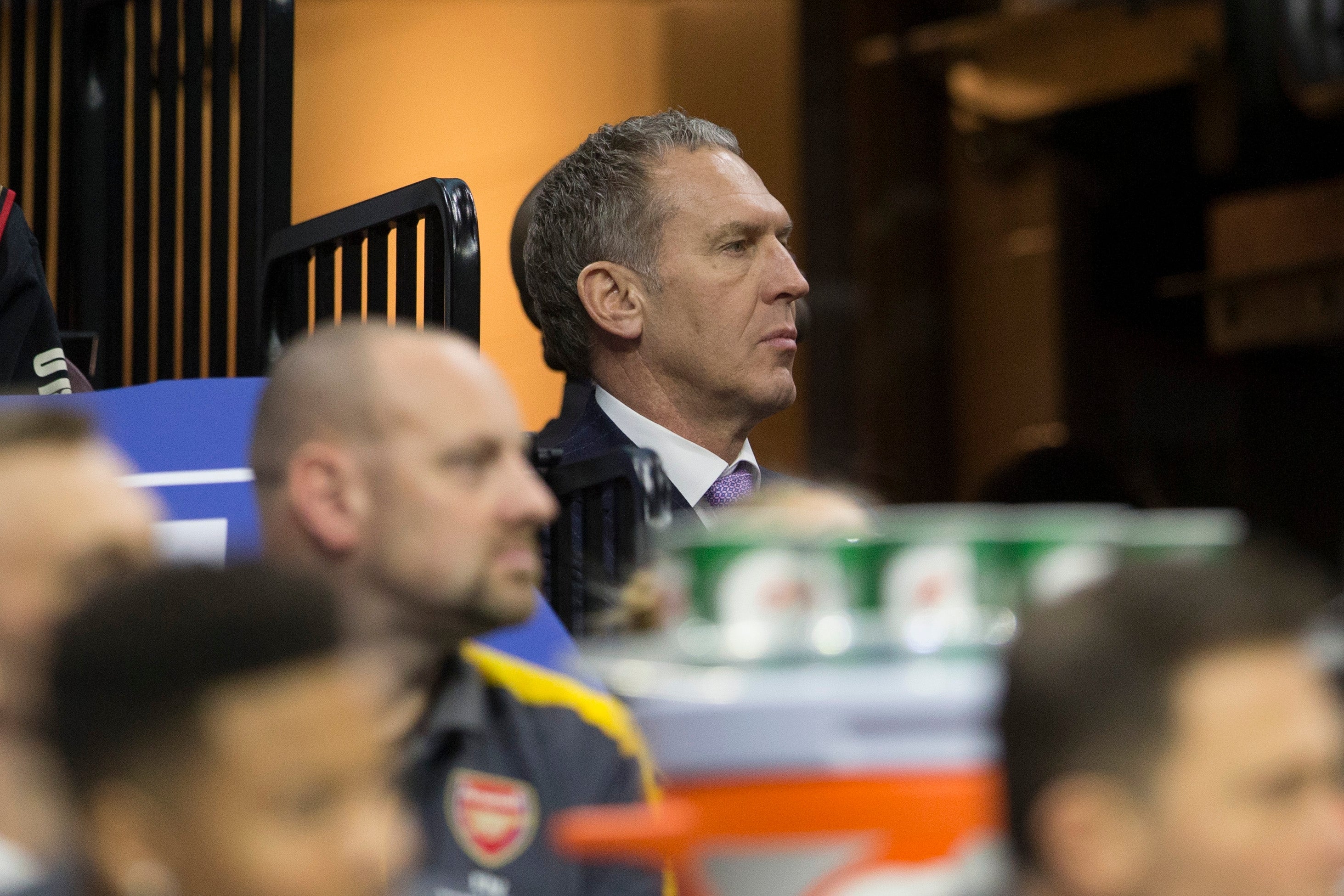 Man successful  a suit   seated, observing a sports event. Other radical   and sports instrumentality  are partially disposable   successful  the foreground