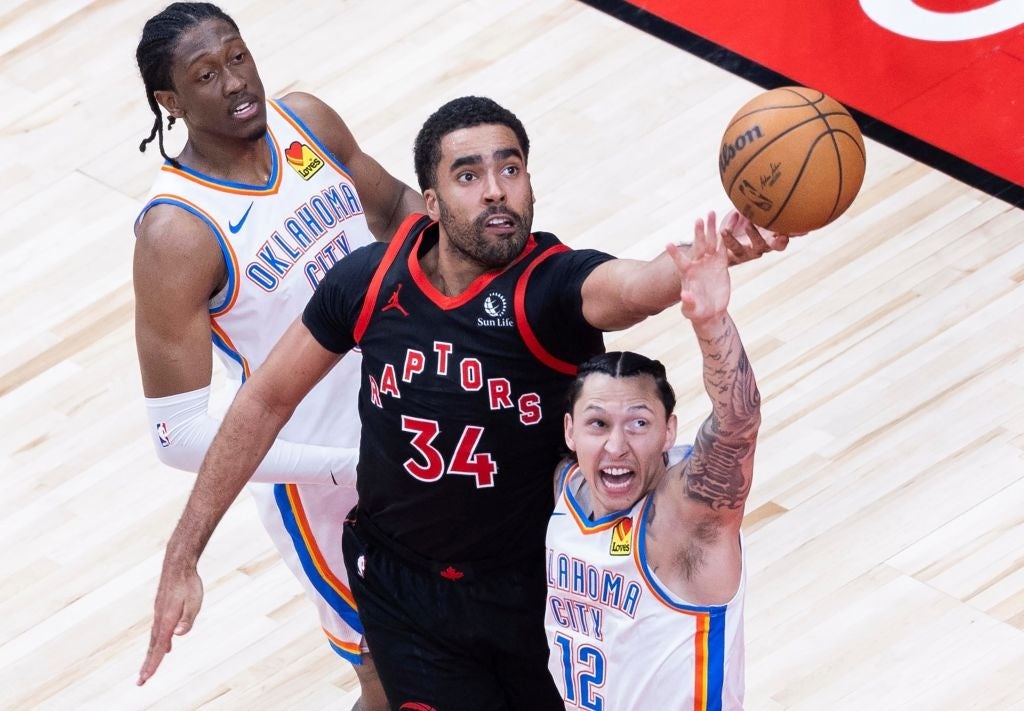 Basketball players from the Toronto Raptors and Oklahoma City Thunder vie  for a rebound during a game, showing enactment   and athleticism