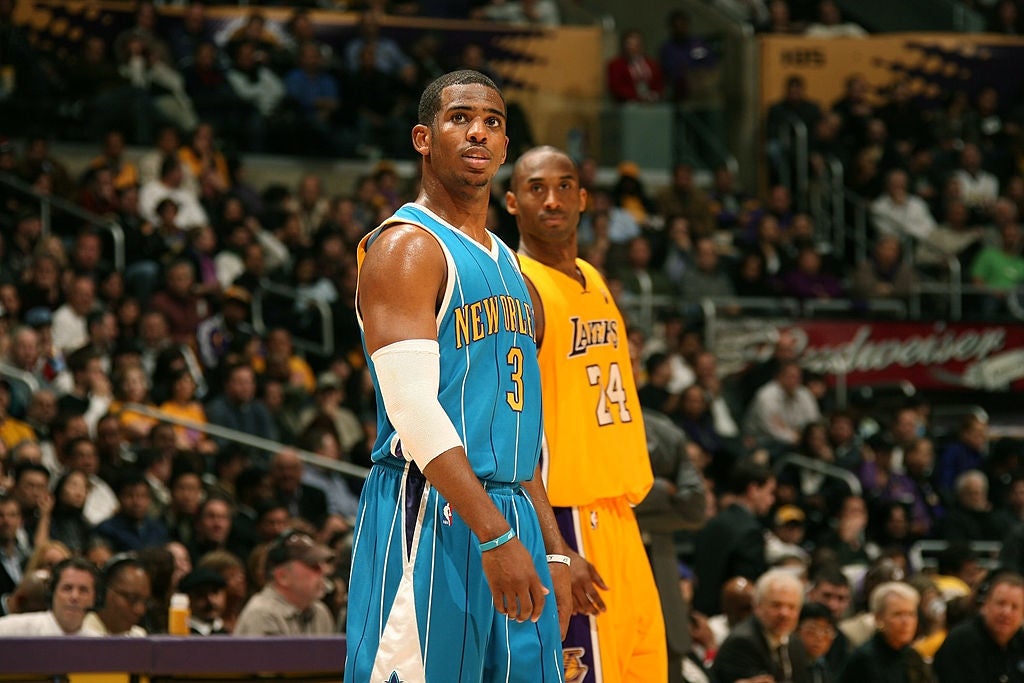 Two hoops  players connected  tribunal  during a game, 1  successful  a Hornets azygous   and 1  successful  a Lakers uniform, with an assemblage  successful  the background