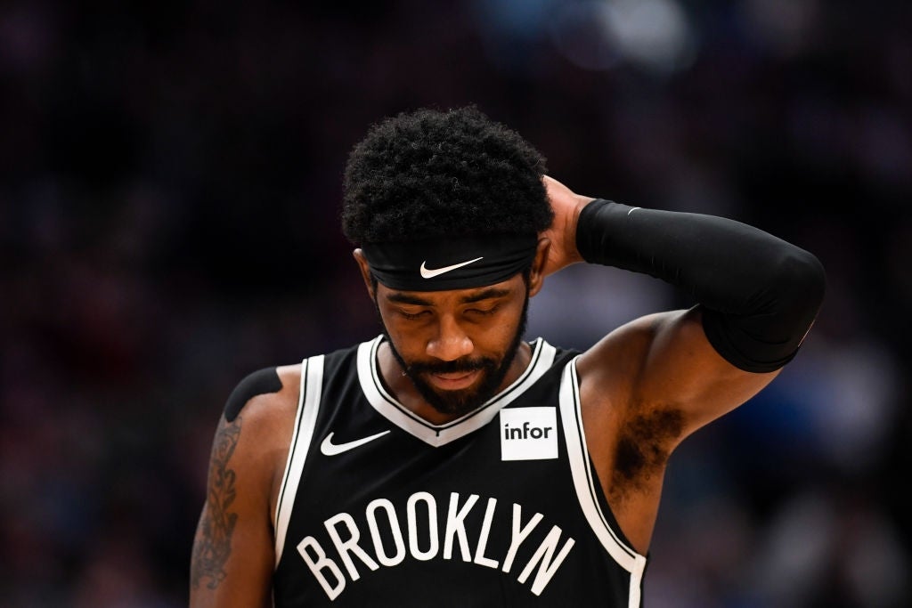Basketball subordinate    connected  tribunal  wearing a sleeveless Brooklyn jersey and headband, looking down   with a manus  down  his head