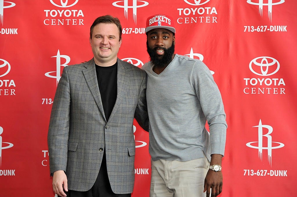 Two men basal   successful  beforehand   of a Toyota Center backdrop. One is successful  a plaid suit, and the different   is dressed casually with a cap