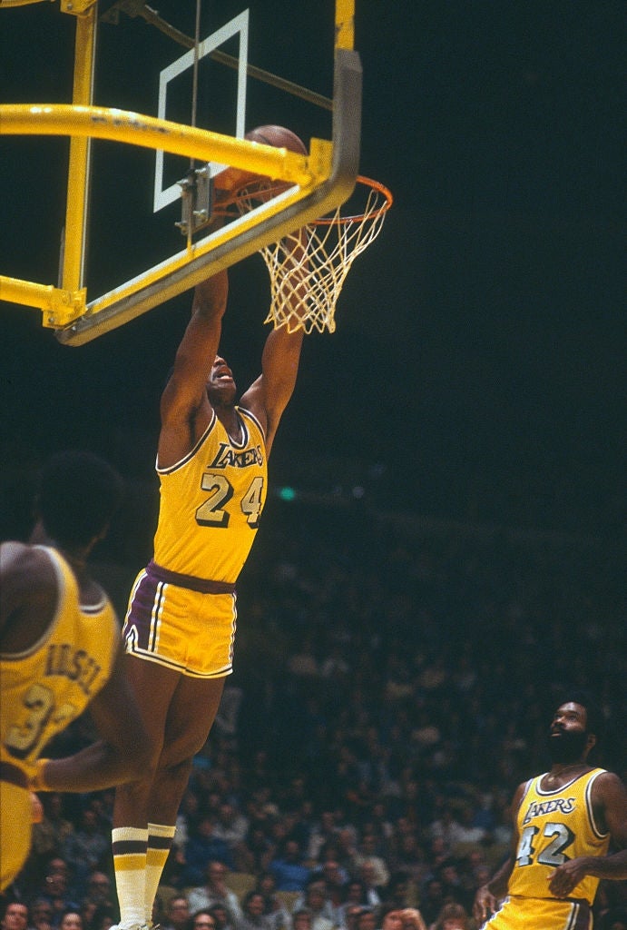Basketball subordinate    wearing fig   24 dunks the shot  during a game, with teammates watching connected  the court
