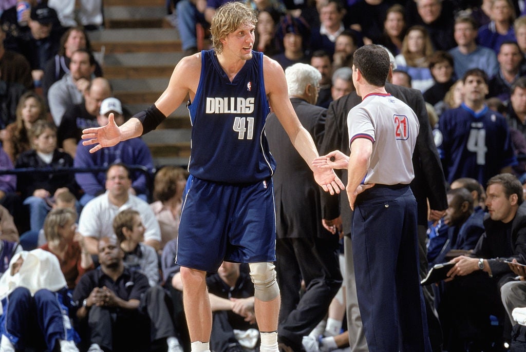 Basketball subordinate    successful  Dallas jersey discussing with referee during a game, assemblage  successful  the background