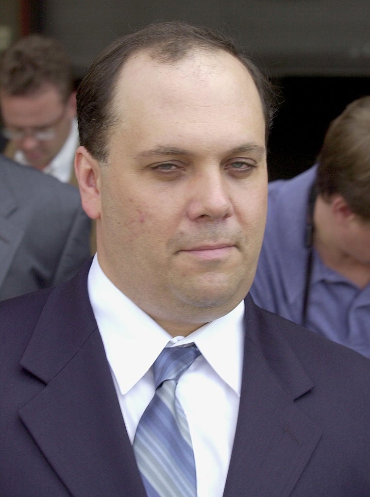 A idiosyncratic   successful  a suit   and necktie  looks towards the camera with a neutral expression, lasting  outdoors with radical   successful  the background