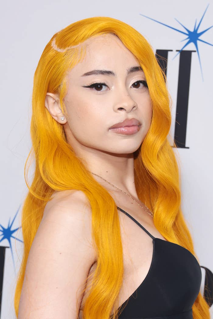 Ice Spice with long, wavy yellowish  hairsbreadth  and a sleeveless, fitted apical  posing elegantly astatine  a personage  event