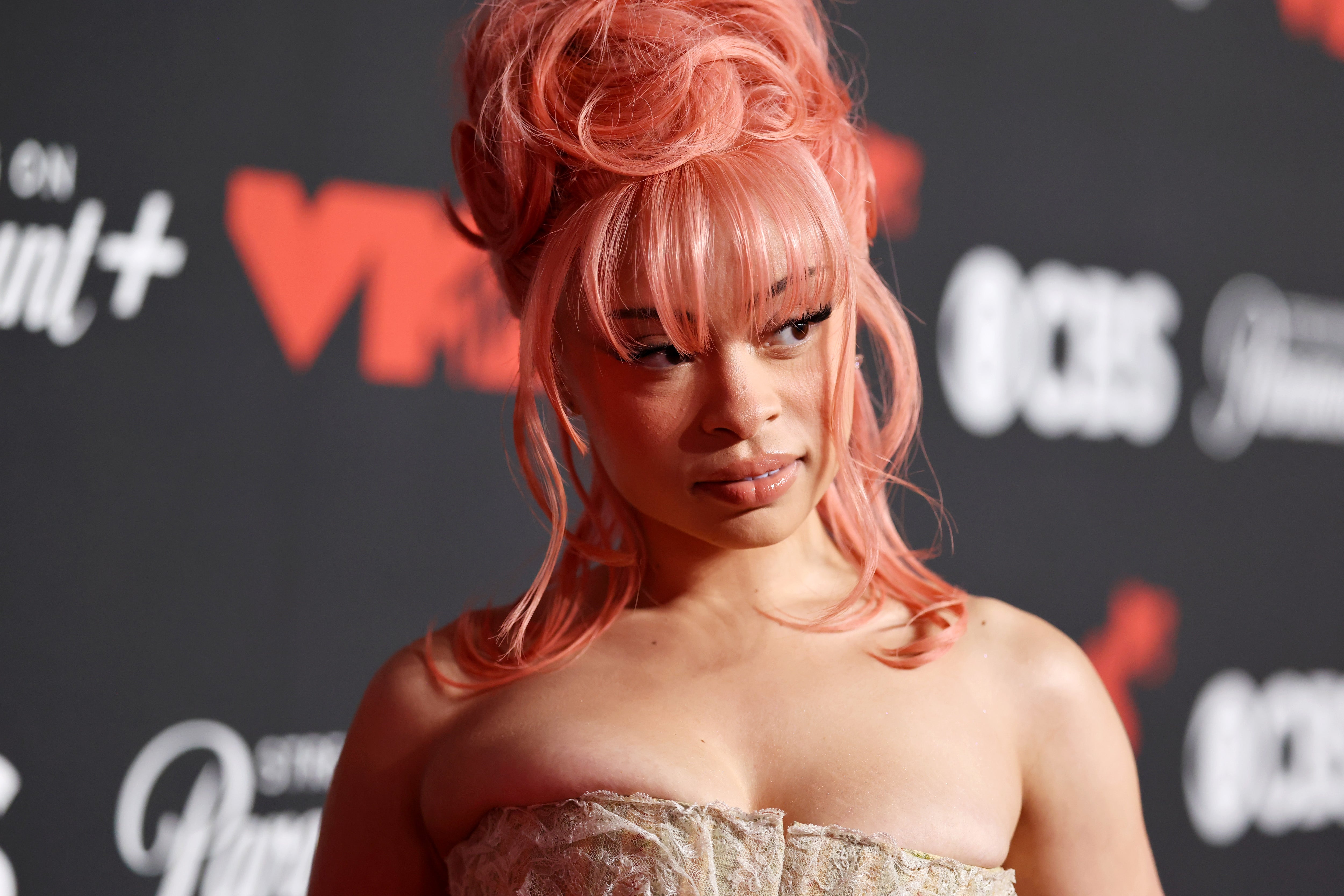 Ice Spice with an elegant, intricate updo and strapless lace outfit on a red carpet