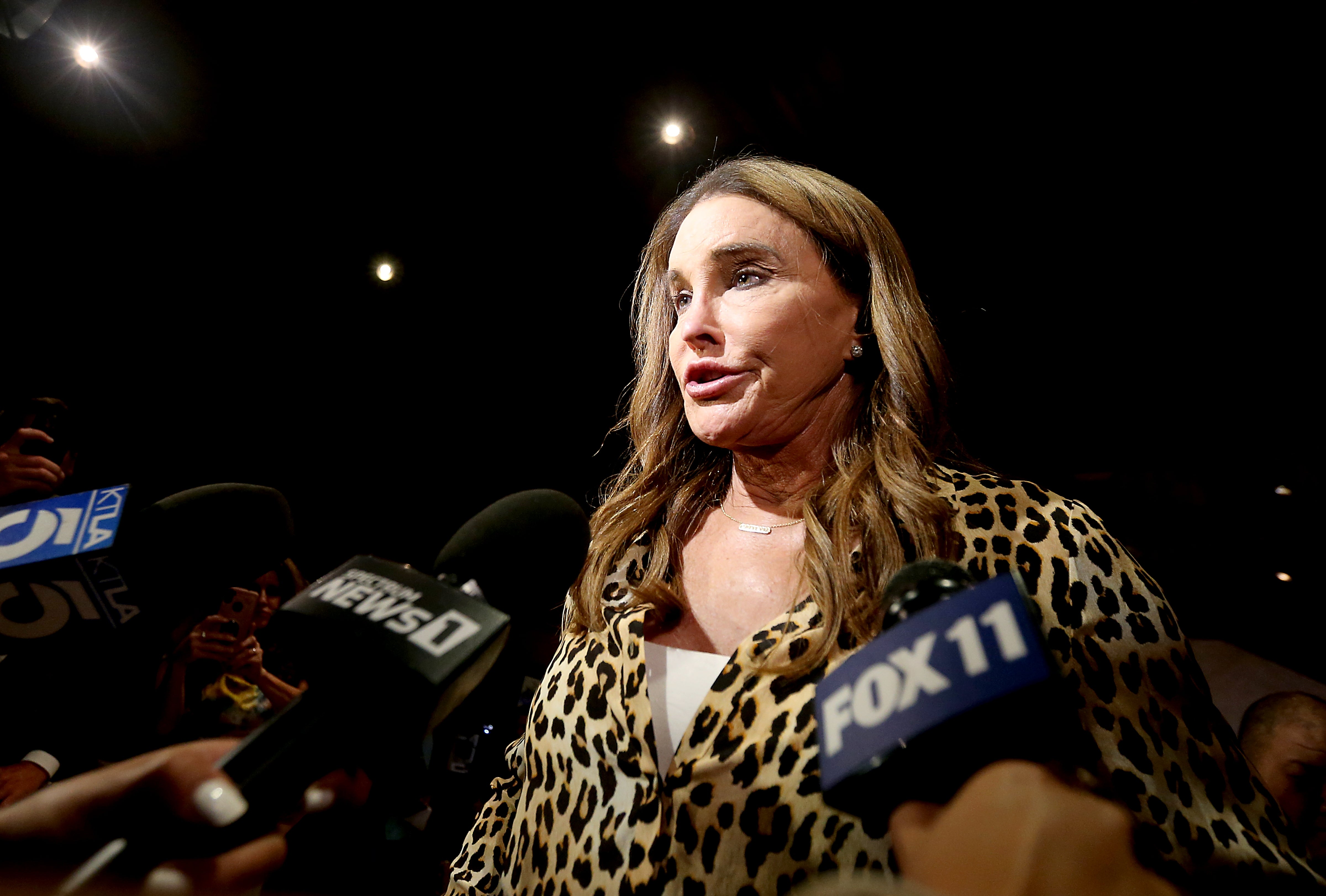 Caitlyn Jenner successful  a leopard people     outfit speaks to reporters surrounded by microphones astatine  a property   event