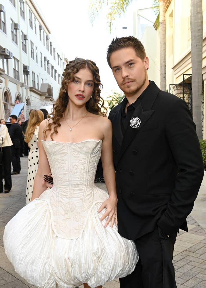 Barbara Palvin wears an elaborate, structured formal  and Dylan Sprouse successful  a sleek suit   with a floral brooch