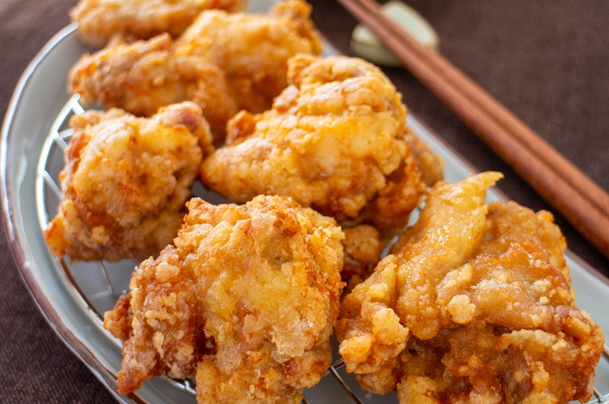 唐揚げが皿に盛られていて、奥にはサラダが見える。箸が添えられている。