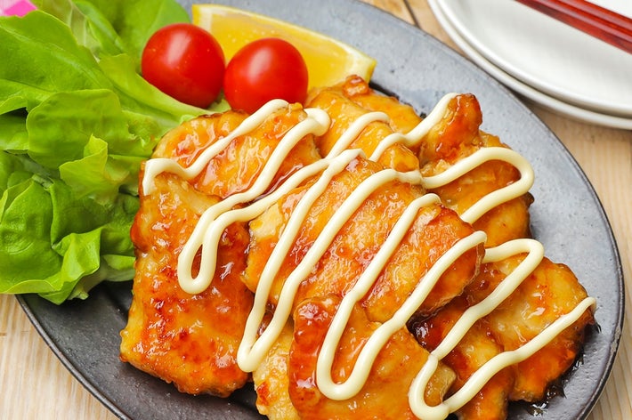皿に盛られた照り焼きチキンとレタス、ミニトマト、レモンが添えられた料理。