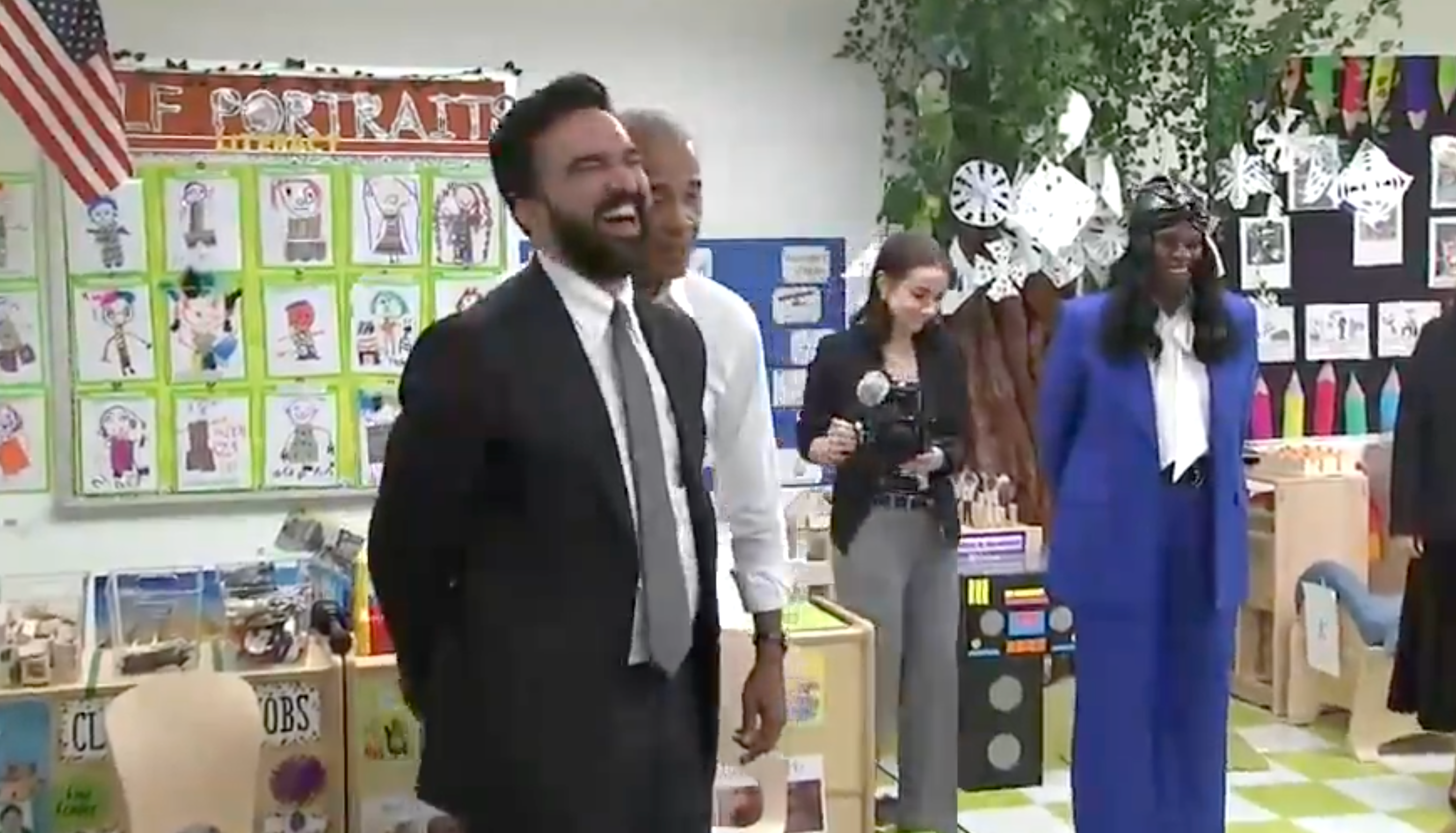 Group of adults wrong  a schoolroom  with children's artwork connected  display, smiling and engaged