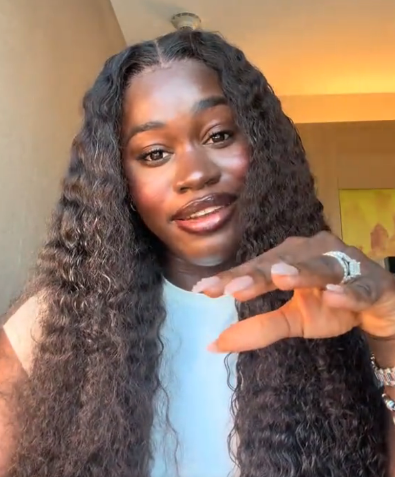 A idiosyncratic   with long, wavy hairsbreadth  gestures with their hand, wearing a airy  apical  and rings, successful  a candid, expressive infinitesimal   indoors