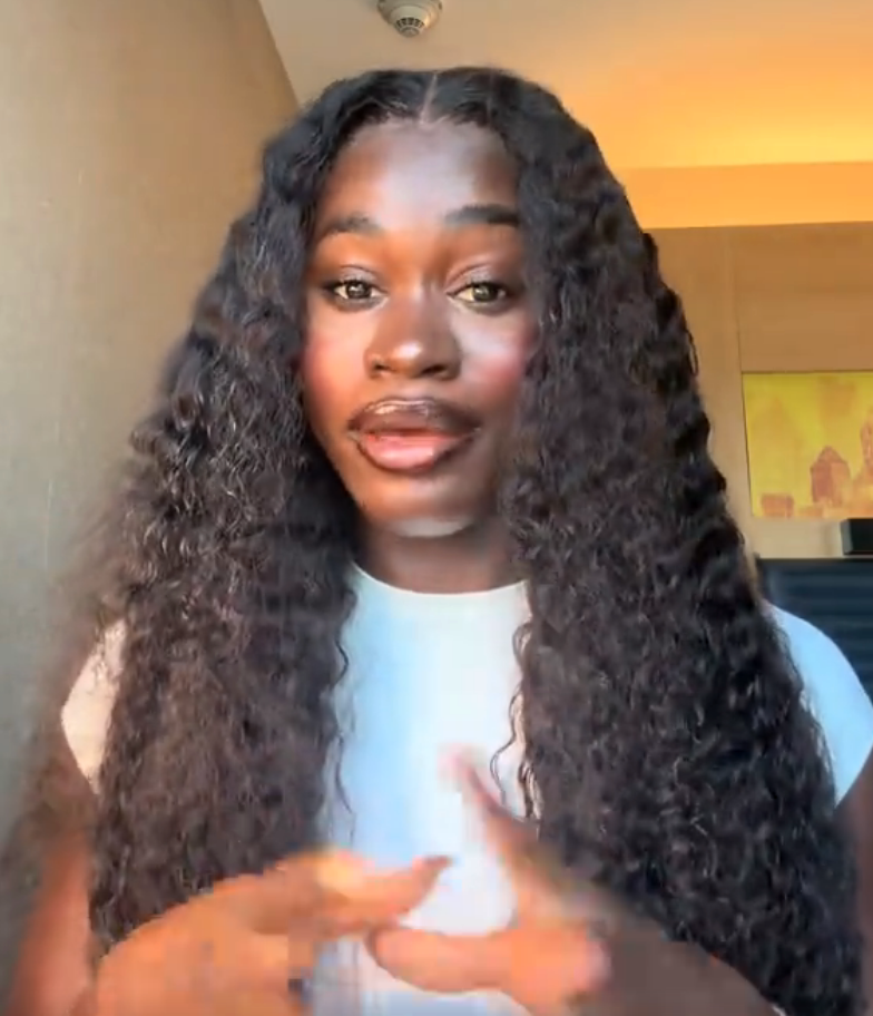 Person with long, curly hairsbreadth  gestures portion    speaking indoors. They've a superior   look  and are wearing a light-colored top