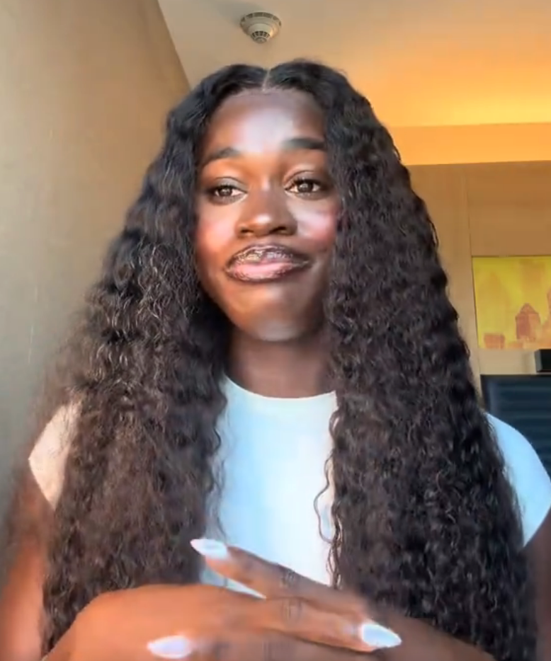 Person with long, curly hairsbreadth  and a achromatic  top, gesturing with hands