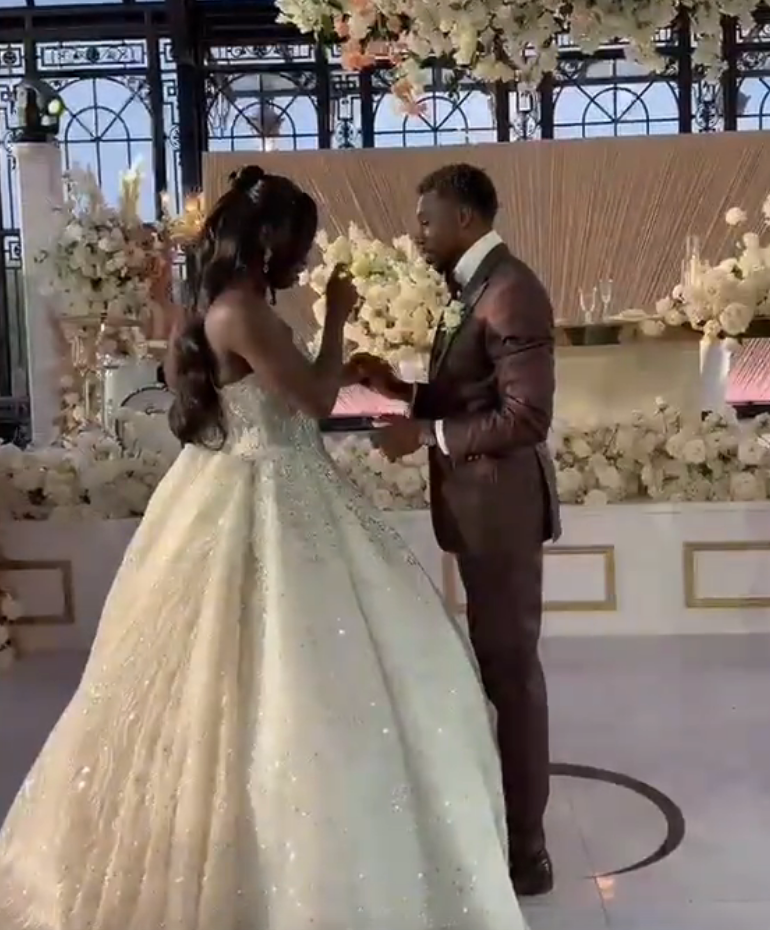 A mates  stands astatine  an elegant wedding venue, exchanging vows. The bride wears a voluminous gown, and the groom is successful  a ceremonial  suit