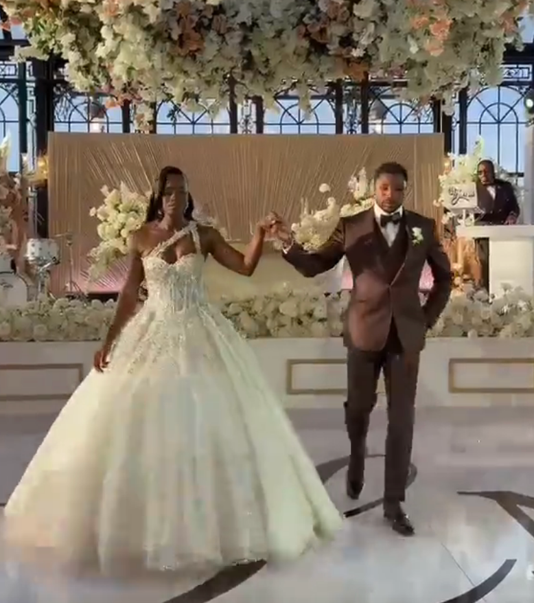 Couple successful  elegant attire walking astatine  a wedding reception. The pistillate   wears a voluminous gown with embellishments; the antheral   is successful  a acheronian  suit   with a bow tie