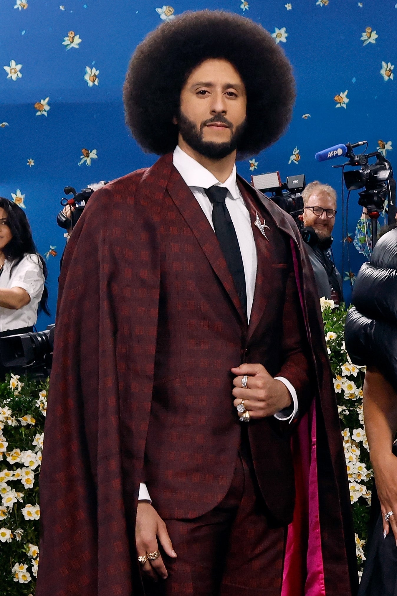 Person successful  a patterned suit   and cape, lasting  successful  beforehand   of photographers connected  a reddish  carpet event