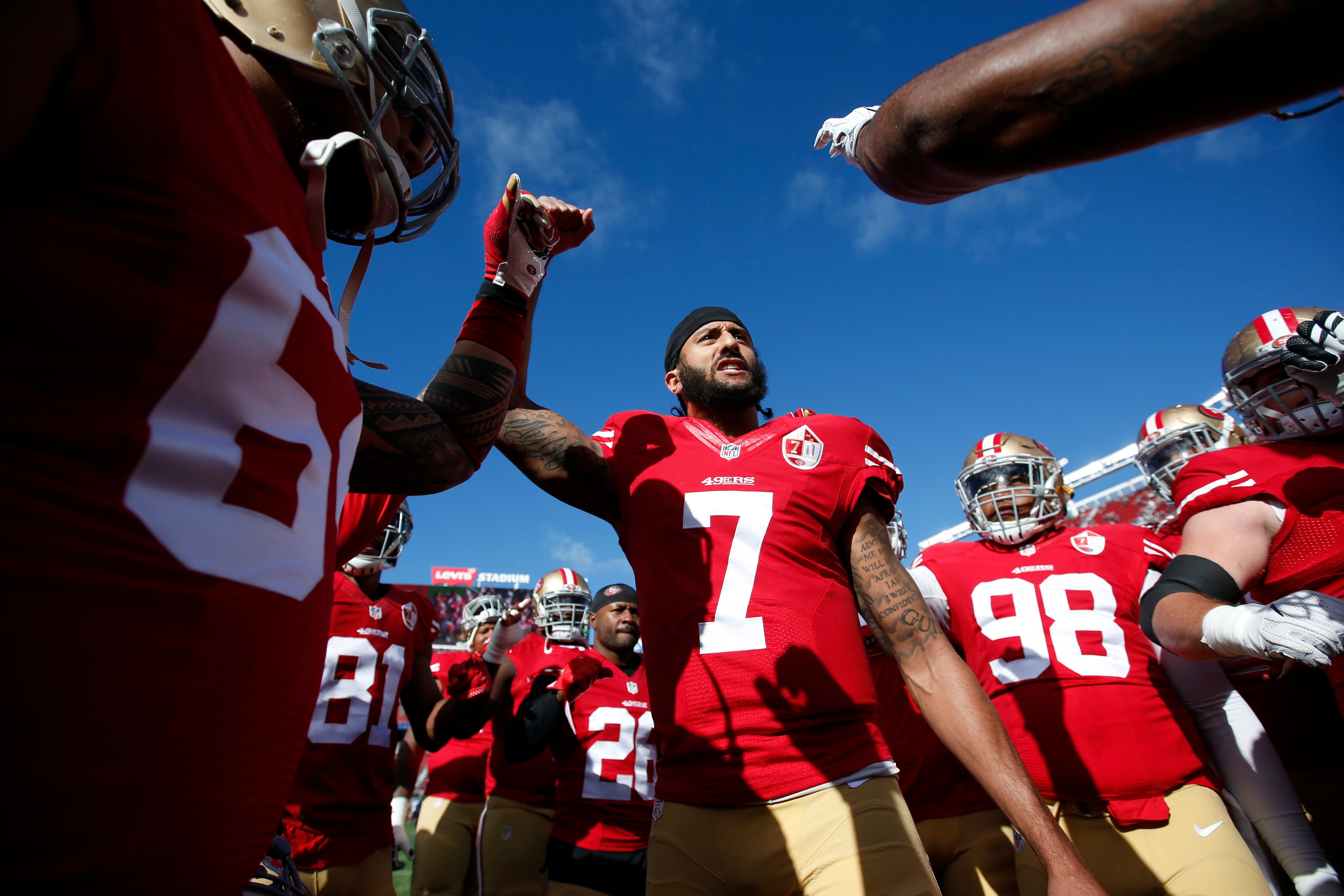 Football squad  players huddle connected  the field, wearing uniforms and helmets, preparing for a crippled  with a focused expression