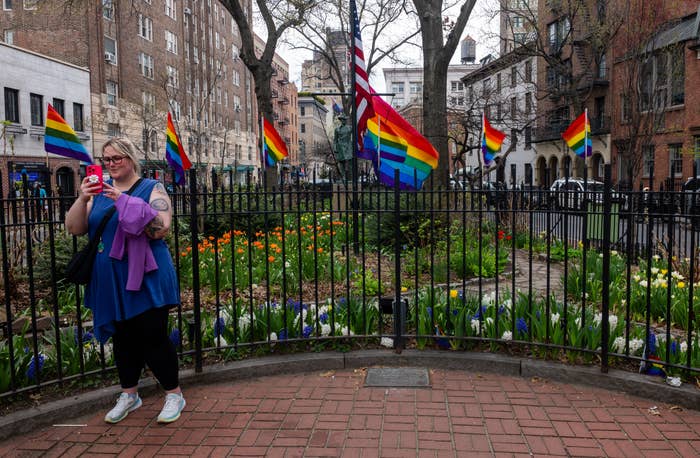 Person successful  casual covering  stands successful  beforehand   of a plot  with aggregate  rainbow flags displayed prominently