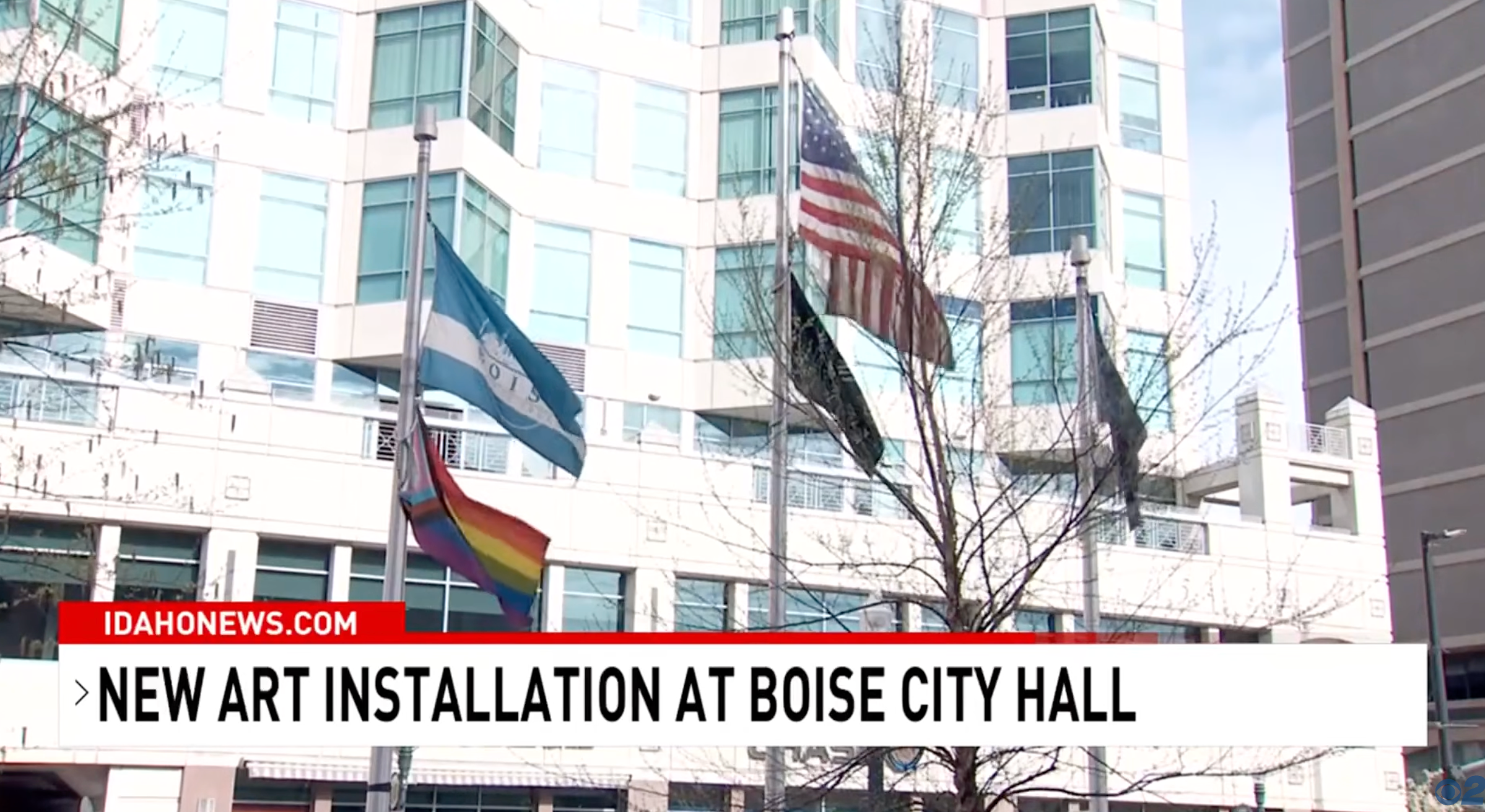 Flags, including a rainbow Pride flag, displayed extracurricular  Boise City Hall. Headline mentions a caller   creation  installation