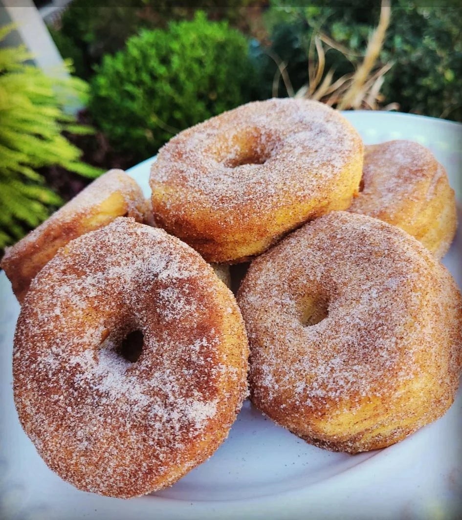 A plate of sugared donuts is stacked, showcasing their fluffy texture and rich coating