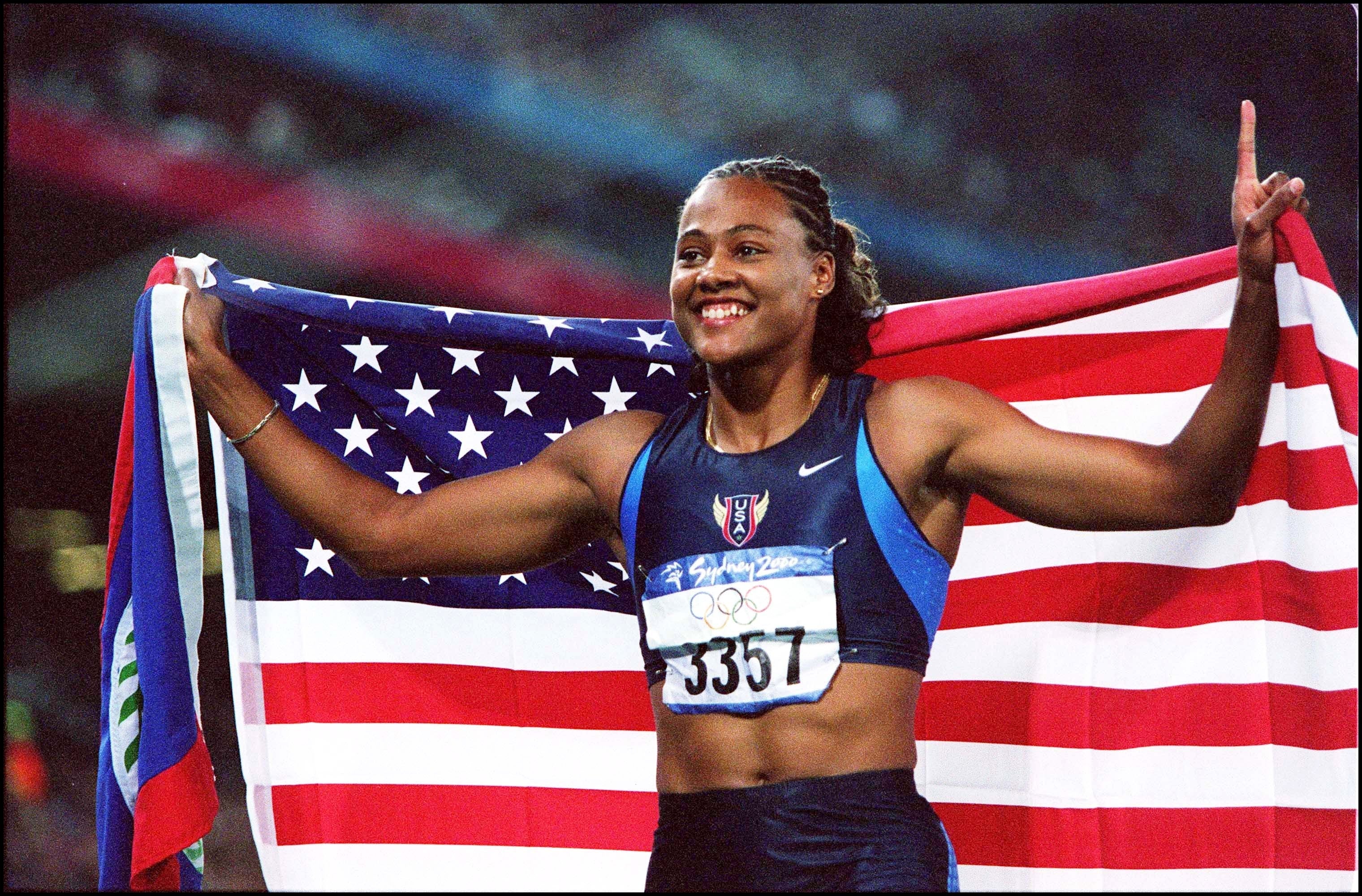 Athlete holding a U.S. emblem  triumphantly astatine  an Olympic event, wearing a sports azygous   with contention    bib fig   3357