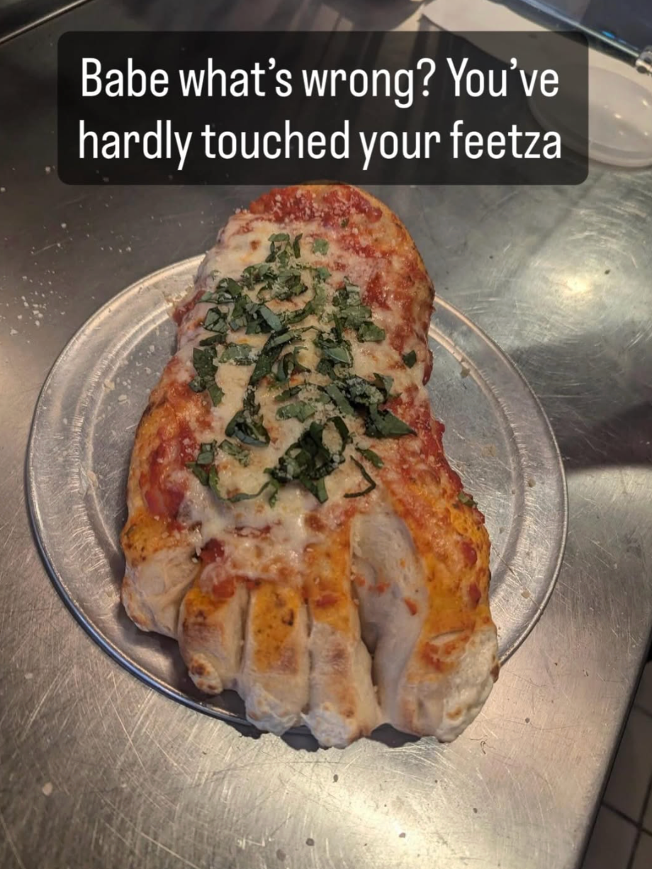 Pizza shaped like a foot, with text saying: "Babe what's wrong? You’ve hardly touched your feetza."