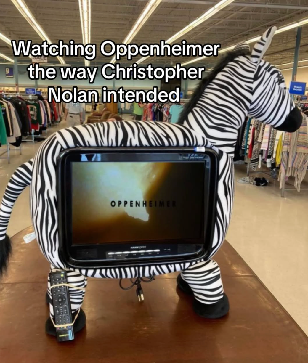 Zebra-shaped TV with "Oppenheimer" on screen, humorous text: "Watching Oppenheimer the way Christopher Nolan intended," in a store setting