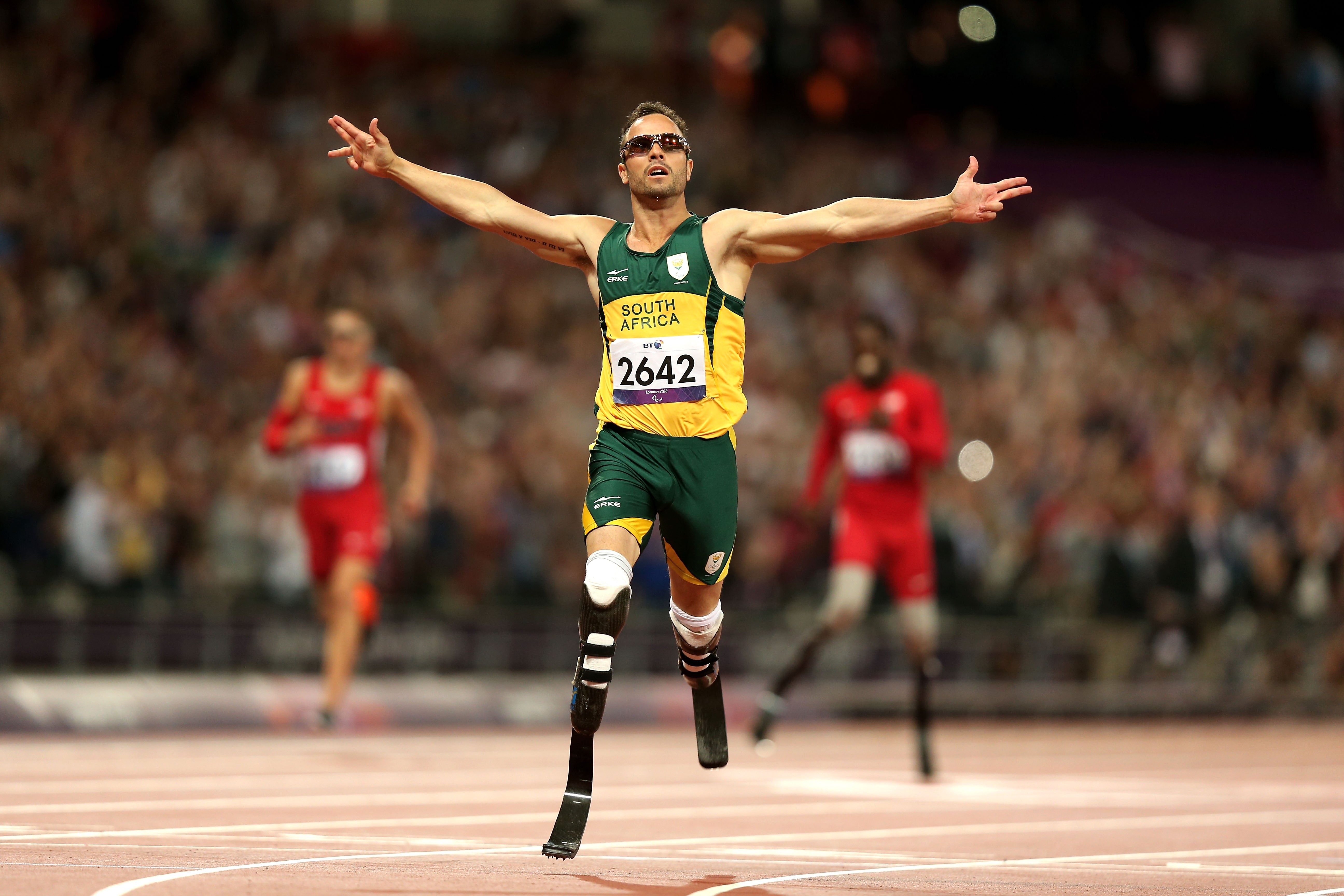 Athlete with prosthetic legs completes a contention    with arms wide   successful  celebration, wearing a competitory  moving  suit