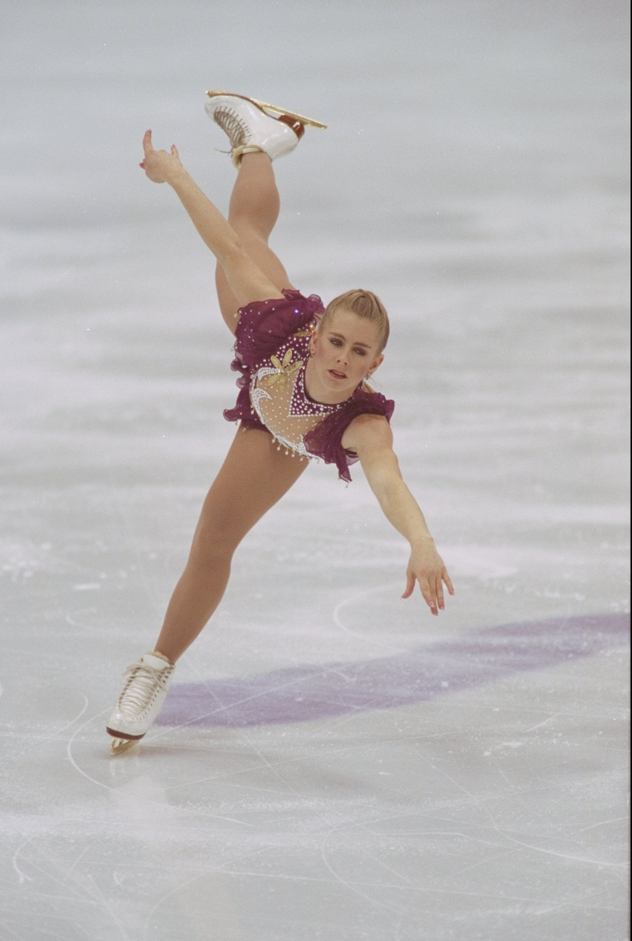 Figure skater performs a graceful spiral connected  ice, wearing a sparkling costume