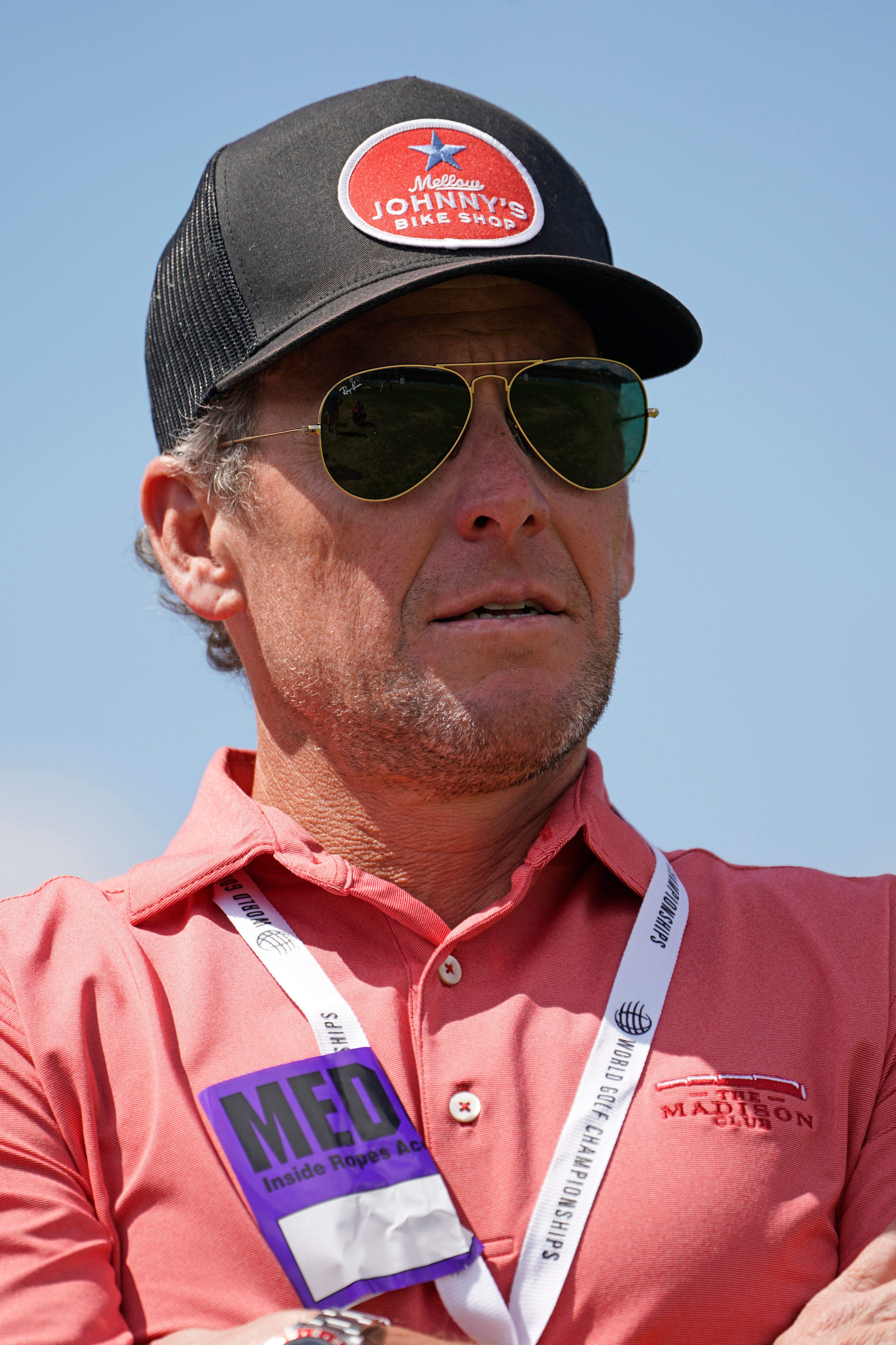 A idiosyncratic   wearing sunglasses, a cap, and a polo garment  with logos, astatine  an outdoor event