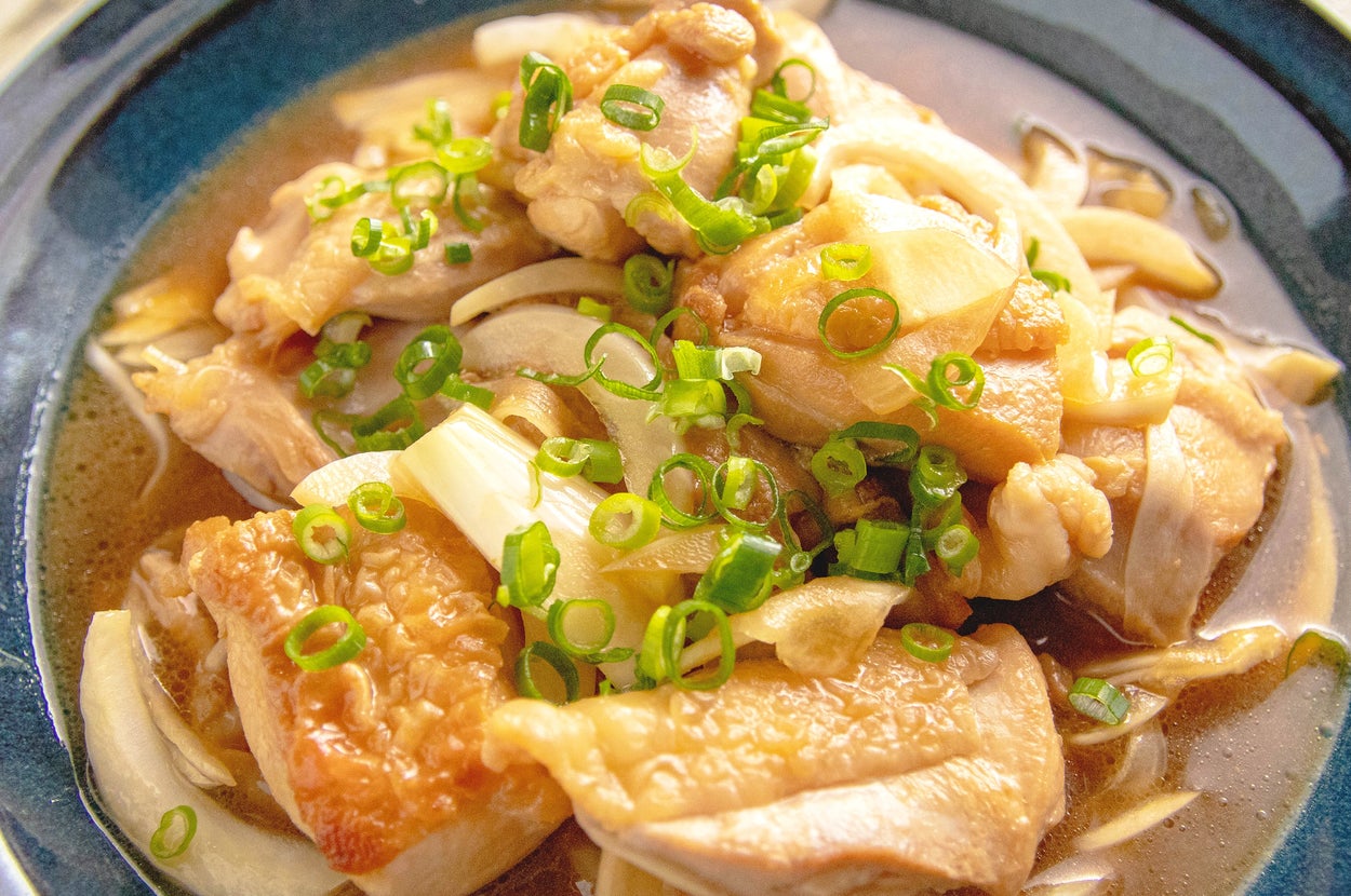 皿に盛られた鶏肉と玉ねぎの煮物。刻みネギが上に乗っている。