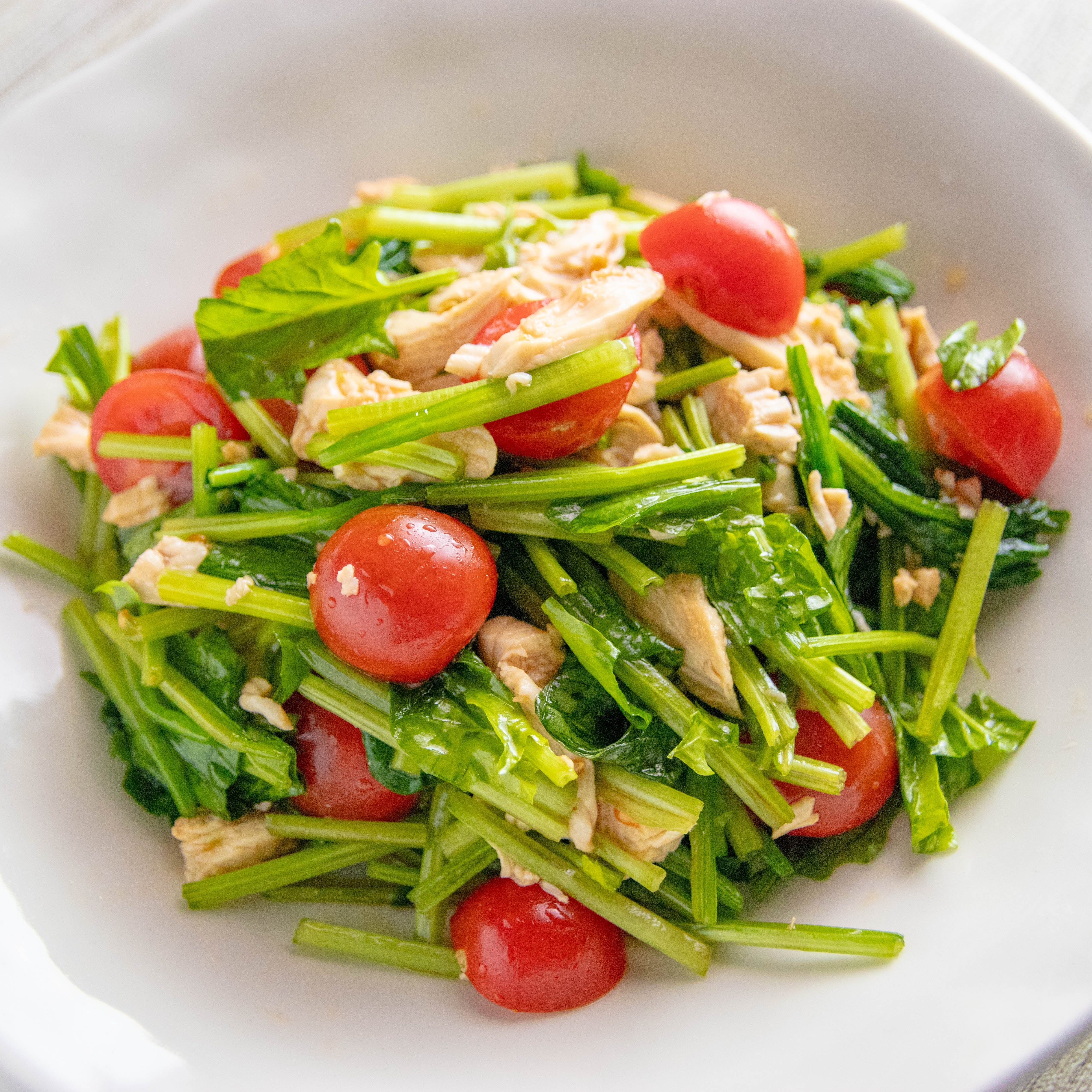トマトと葉野菜、鶏肉のサラダが白い皿に盛られている。