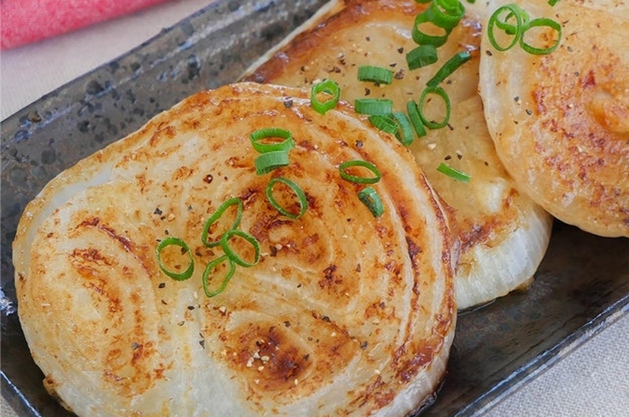 鉄板の上に並んだ焼き回鍋肉風味の玉ねぎパンケーキ、青ネギがトッピングされています。