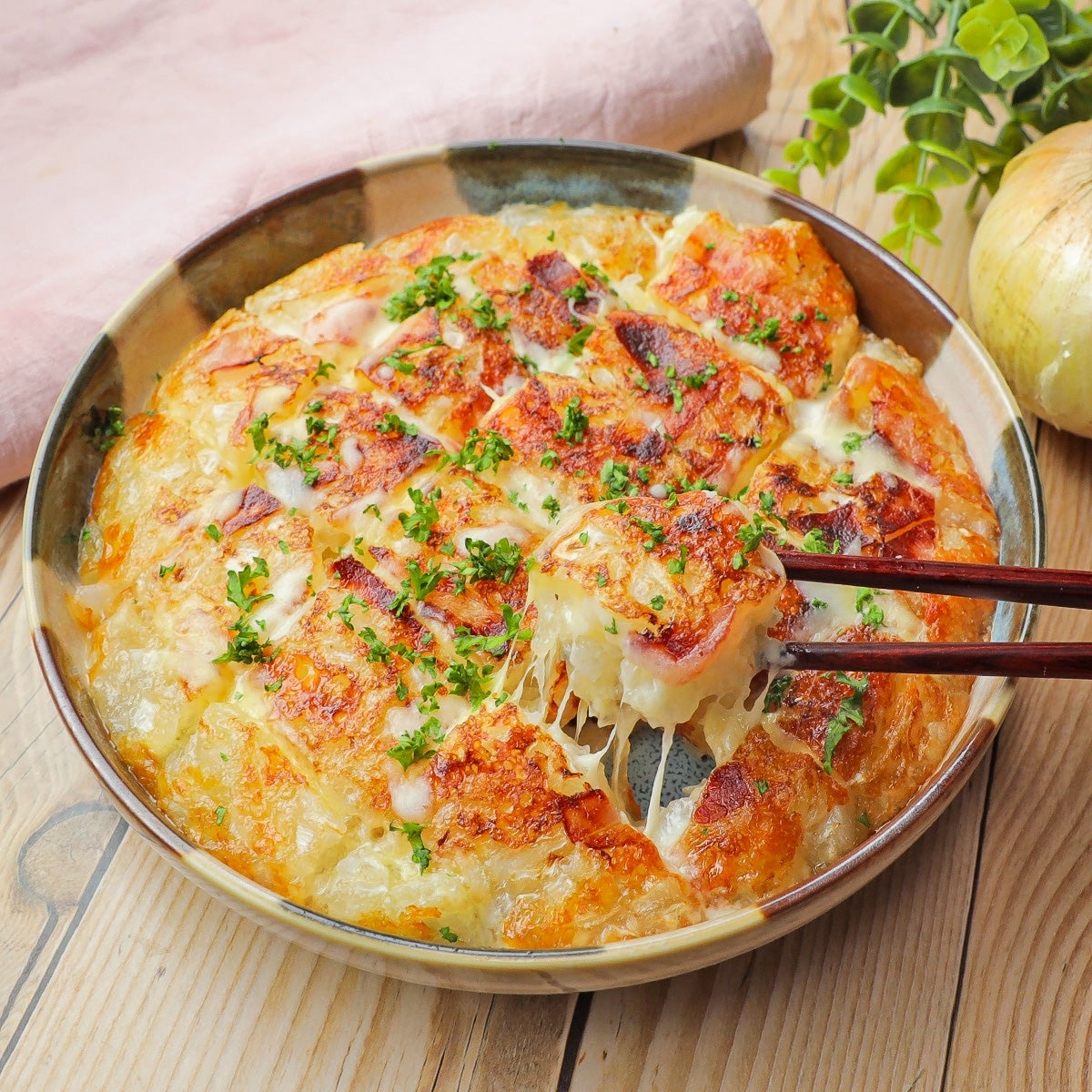チーズがとろけるパン焼き料理を箸で取る様子。