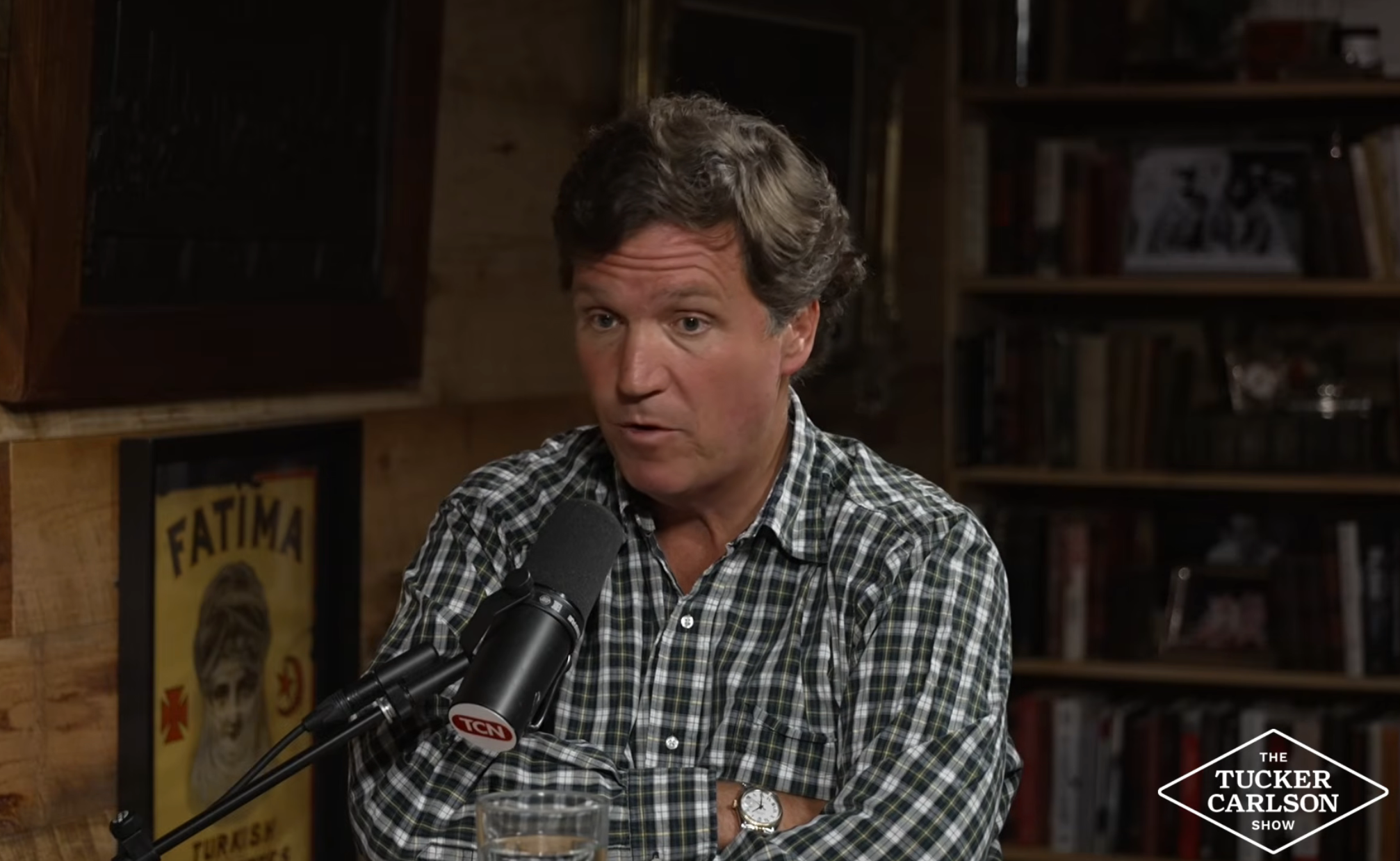 Person speaking into a microphone during a speech   show. The inheritance  includes bookshelves and a poster