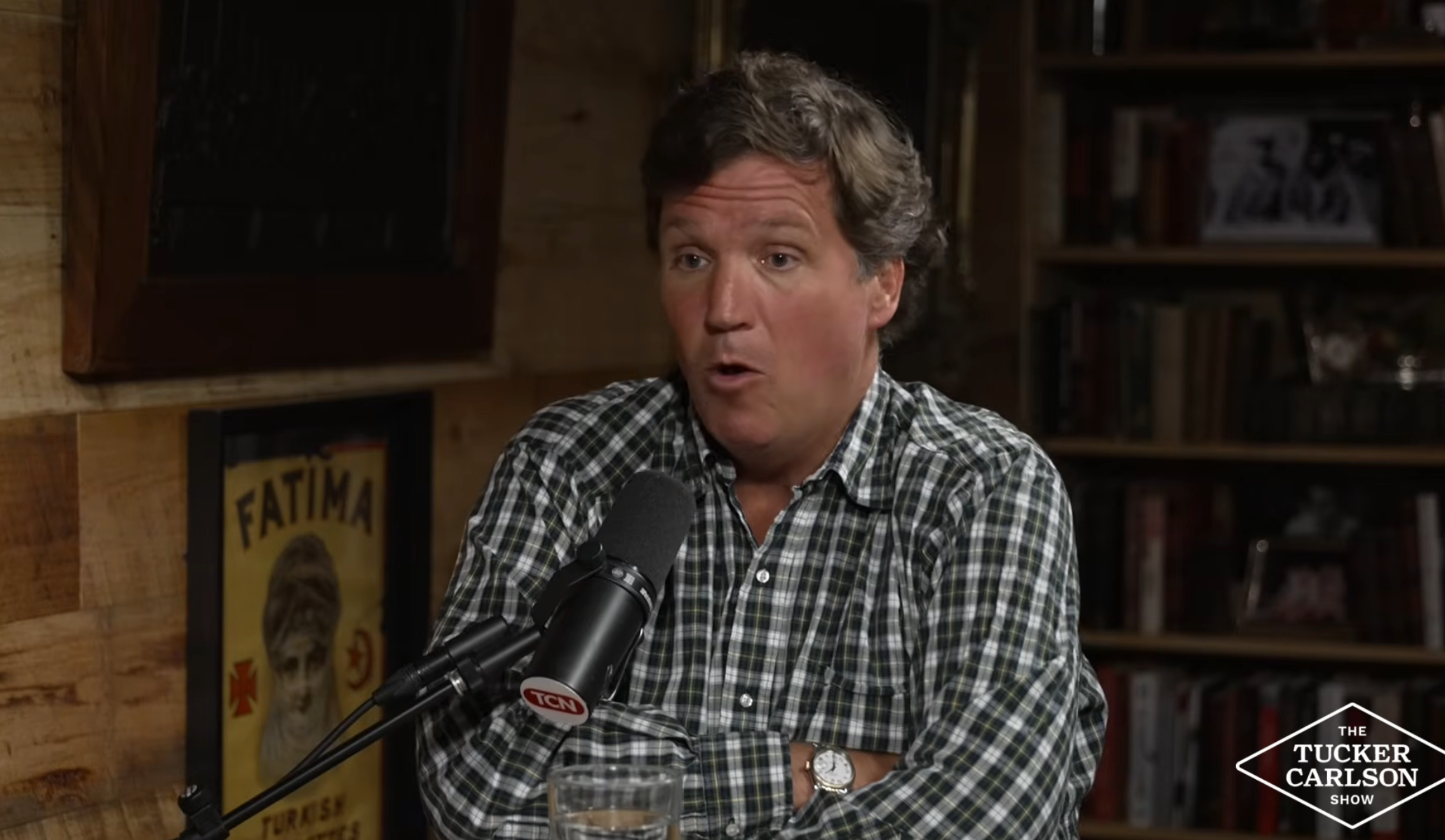 Man speaking into a microphone connected  a speech   amusement   set, wearing a checkered shirt