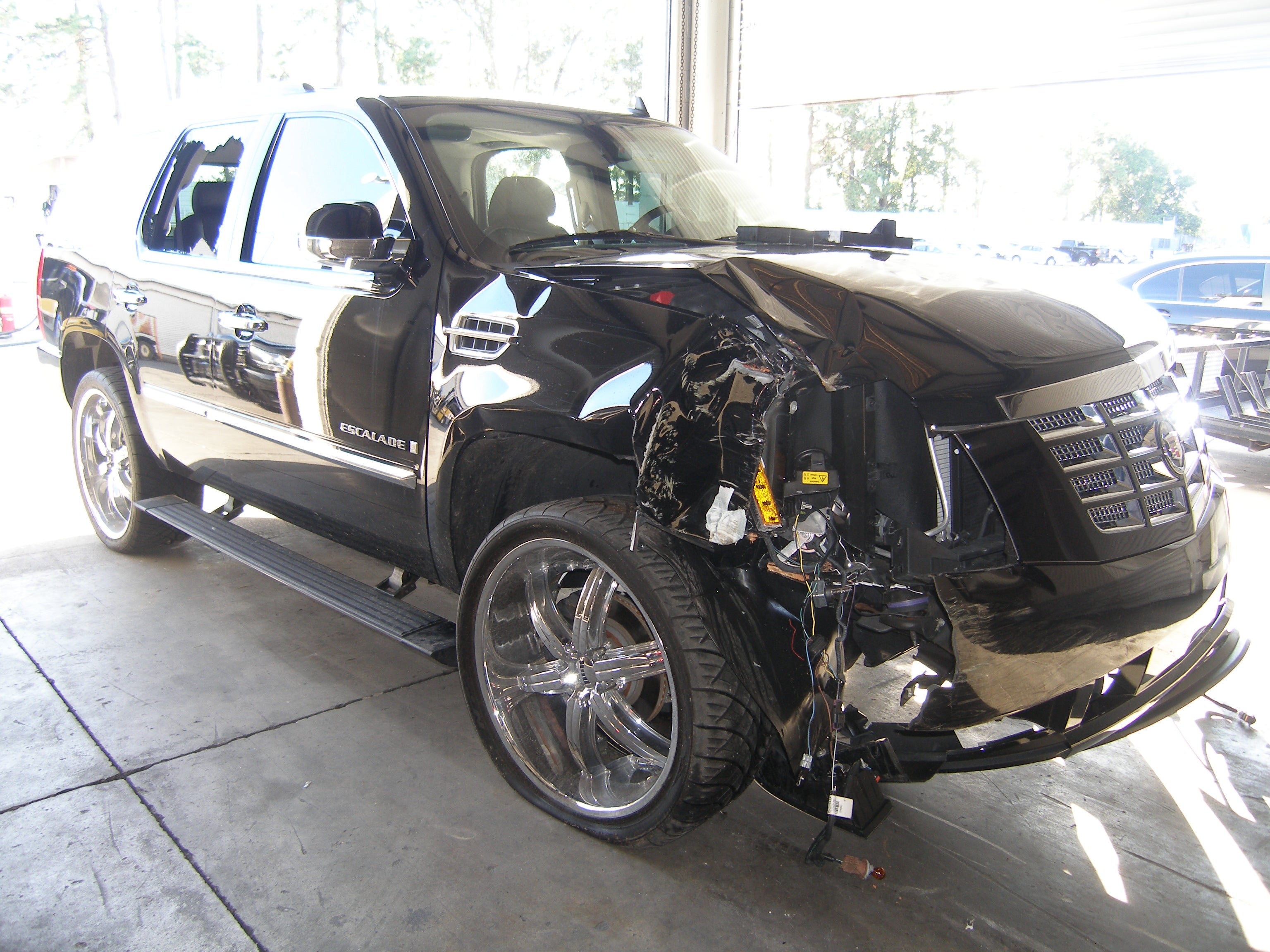 Damaged achromatic  SUV with front-end collision, parked successful  a garage. The conveyance  shows important    dents and a bent wheel