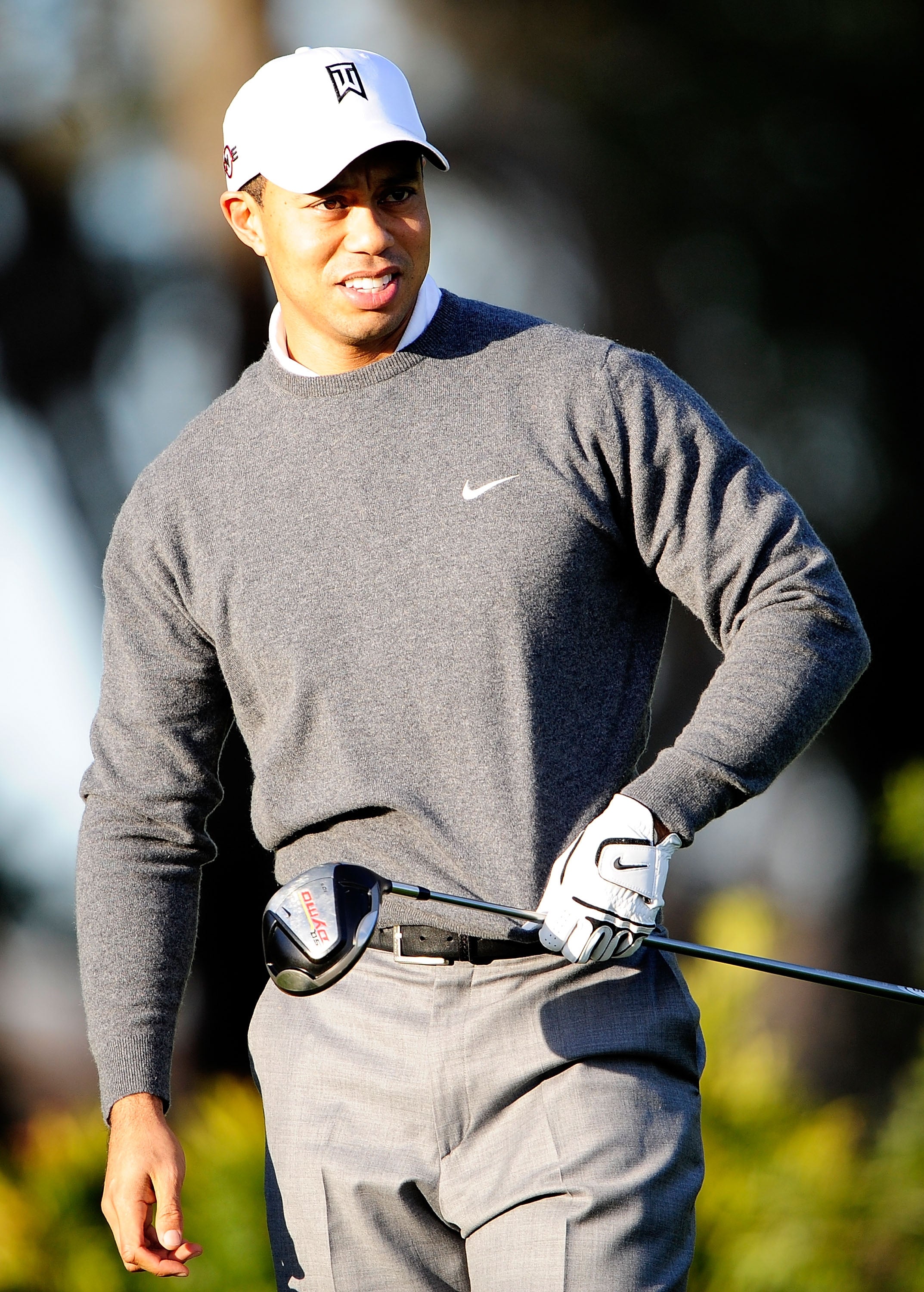 Golfer successful  a grey  sweater and headdress  with a logo, holding a operator  connected  a play  course, smiling