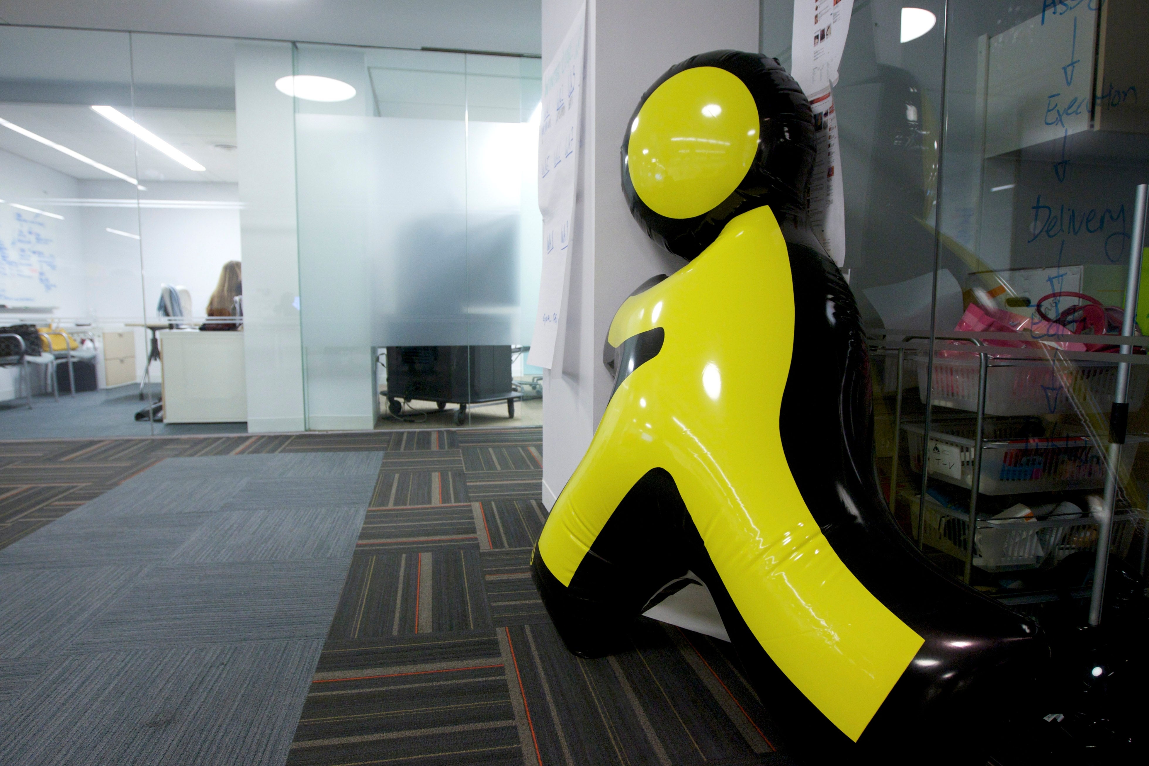 Inflatable AOL Instant Messenger logo prop leaning against a solid  partition  successful  a modern   bureau   setting