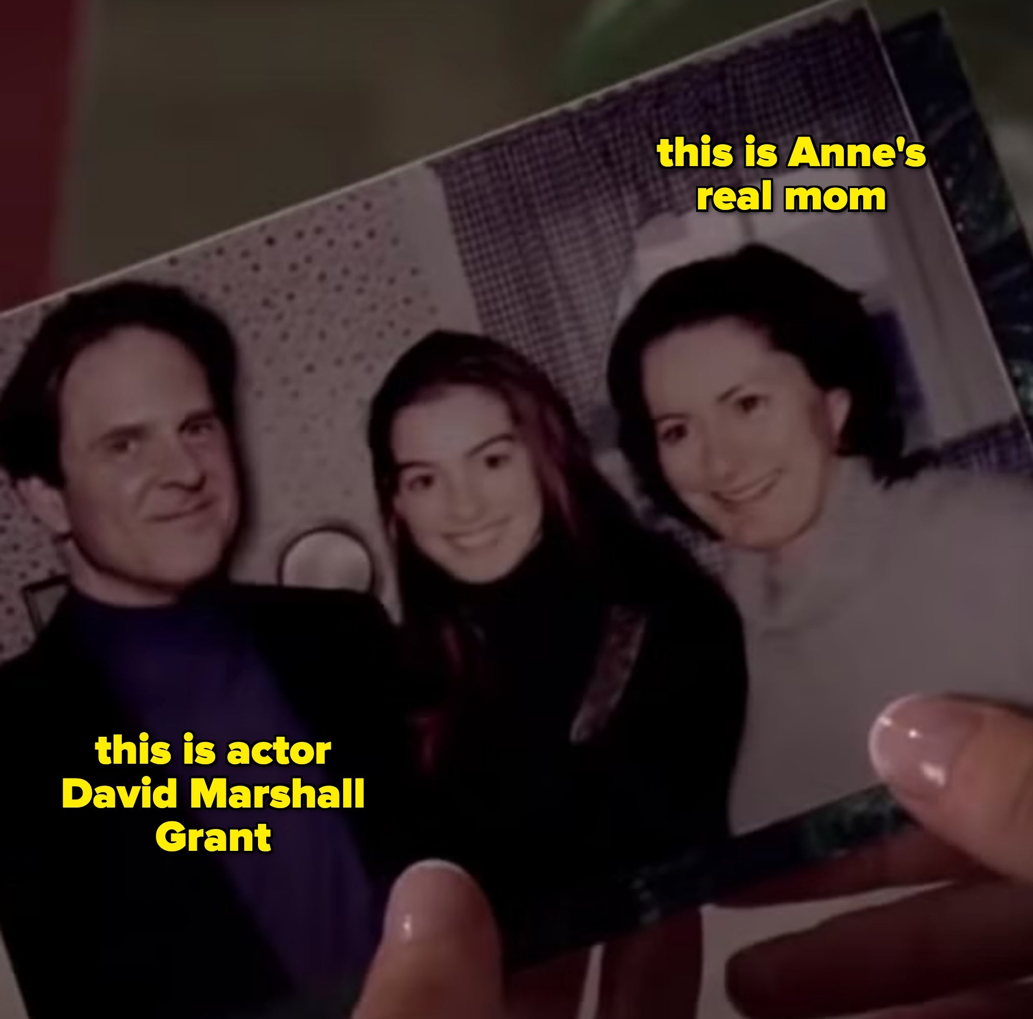 A idiosyncratic   holds an aged  household  photograph  showing 3  radical   smiling indoors