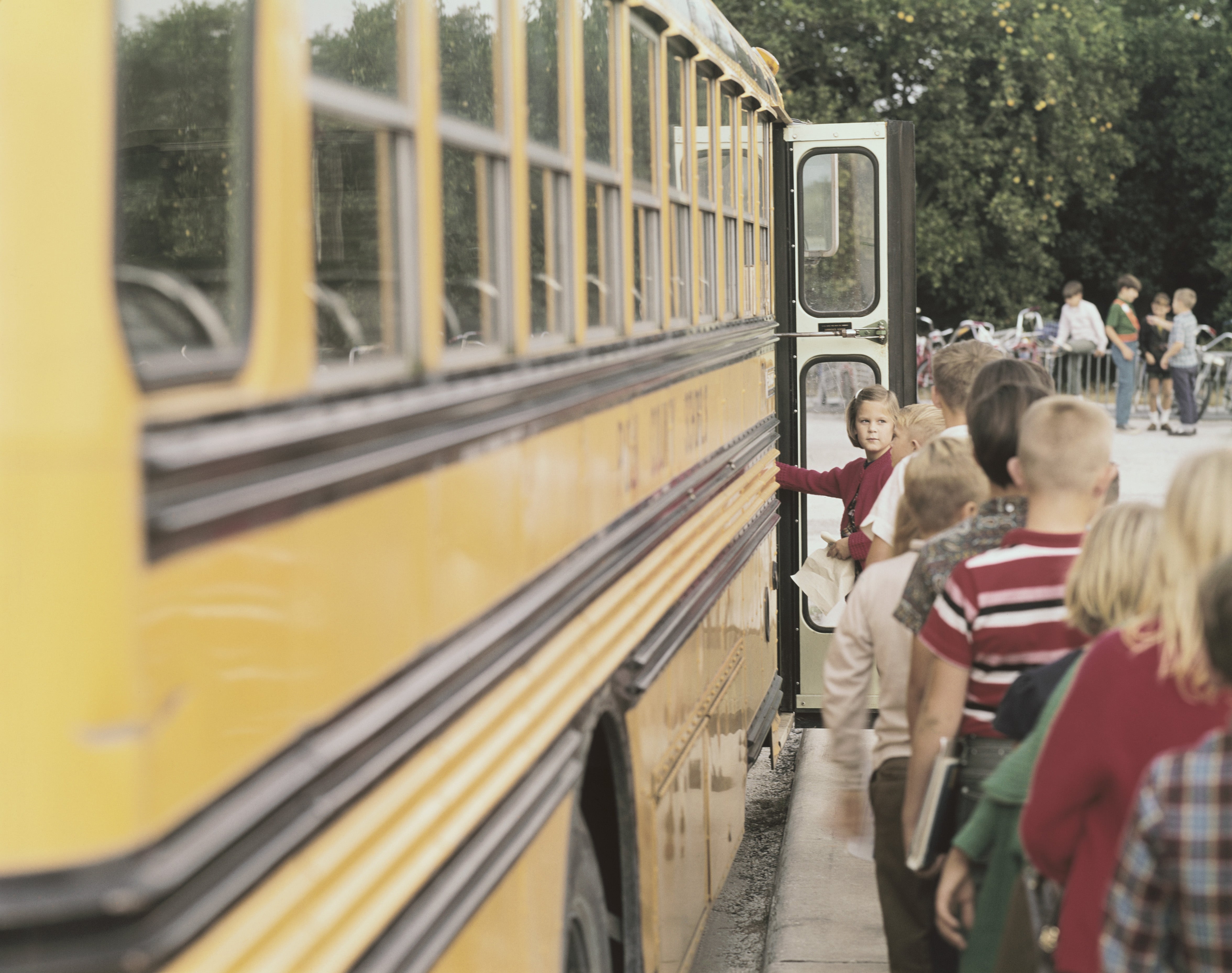 A kid  gestures towards a yellowish  schoolhouse  autobus  doorway  arsenic  children enactment     up   to board, evoking a consciousness   of nostalgia