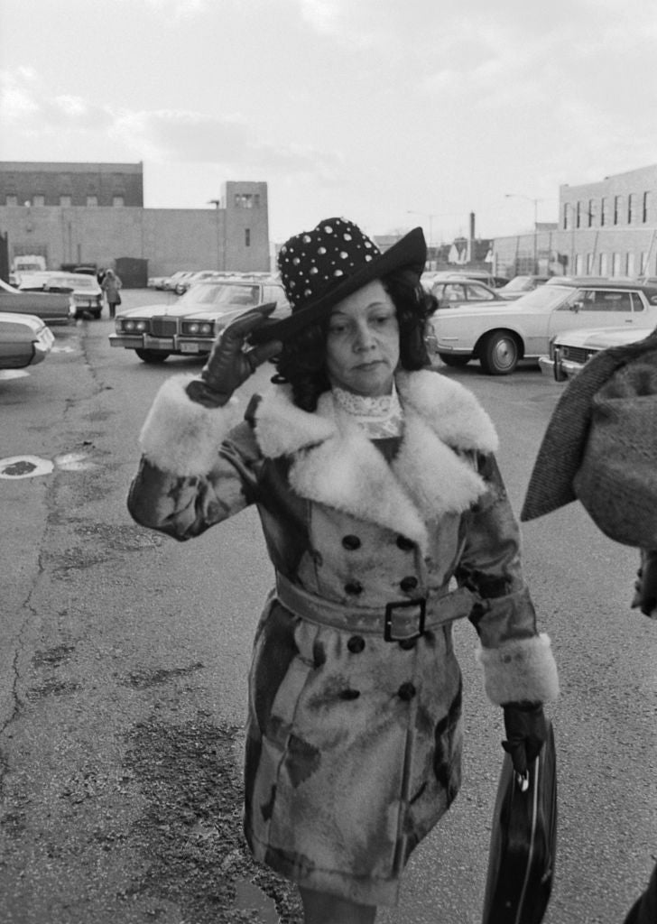 A pistillate   successful  a fur-trimmed overgarment  and chapeau  walks done  a parking batch  successful  a vintage, stylish outfit